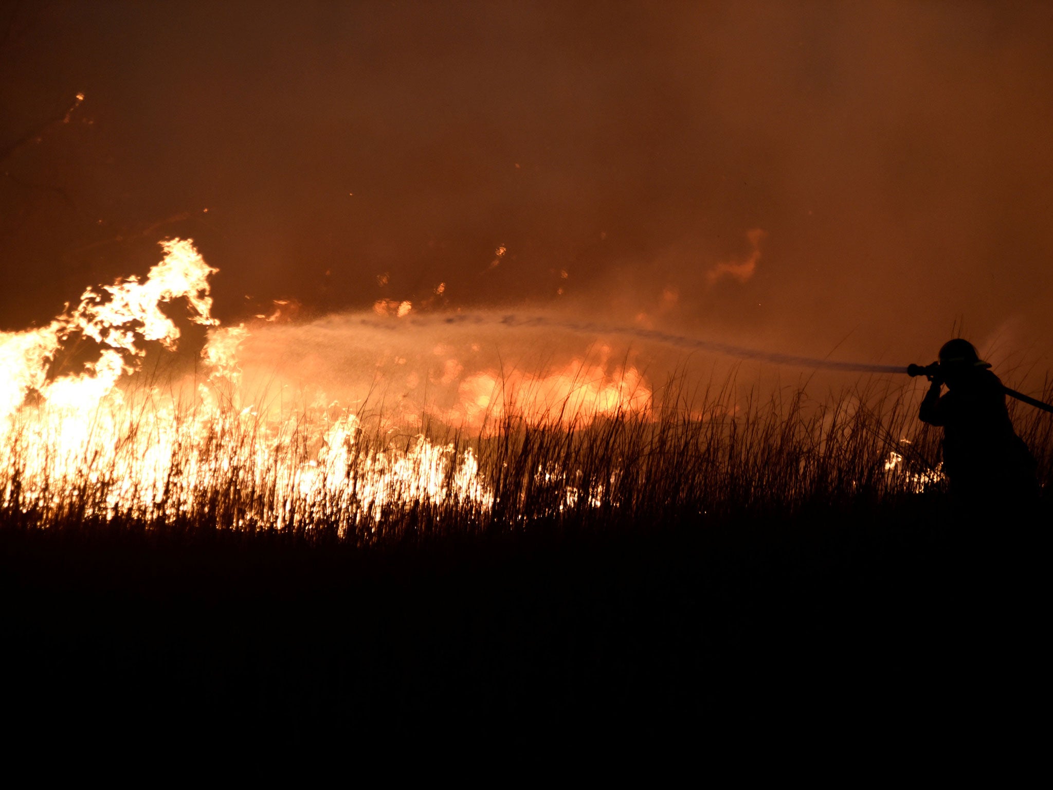 A firefighter works to control the Rhea Fire near Seiling, Oklahoma