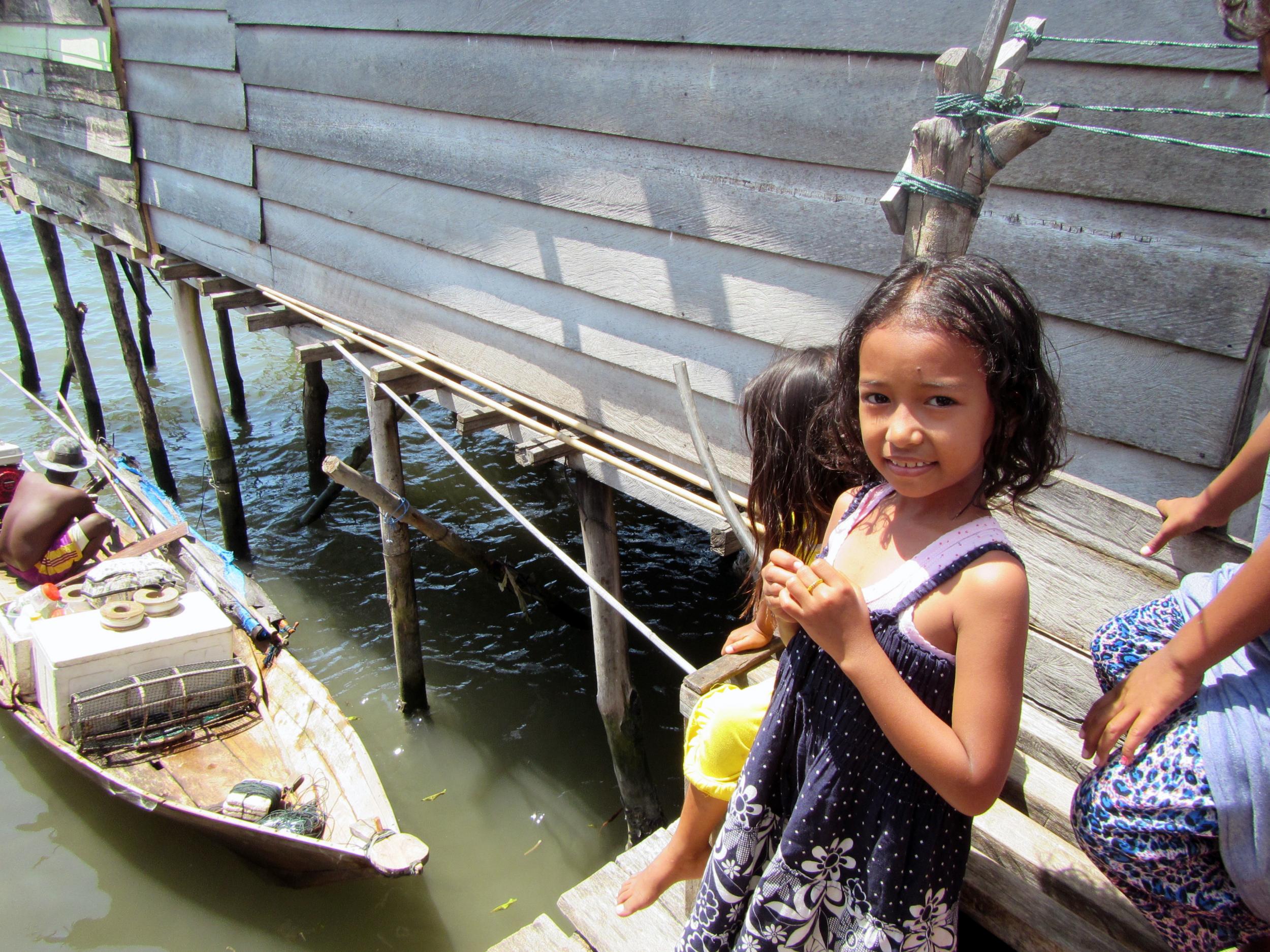 A young Bajau girl looks on in excitement as her father, a traditional Bajau diver, returns from a two-week fishing trip