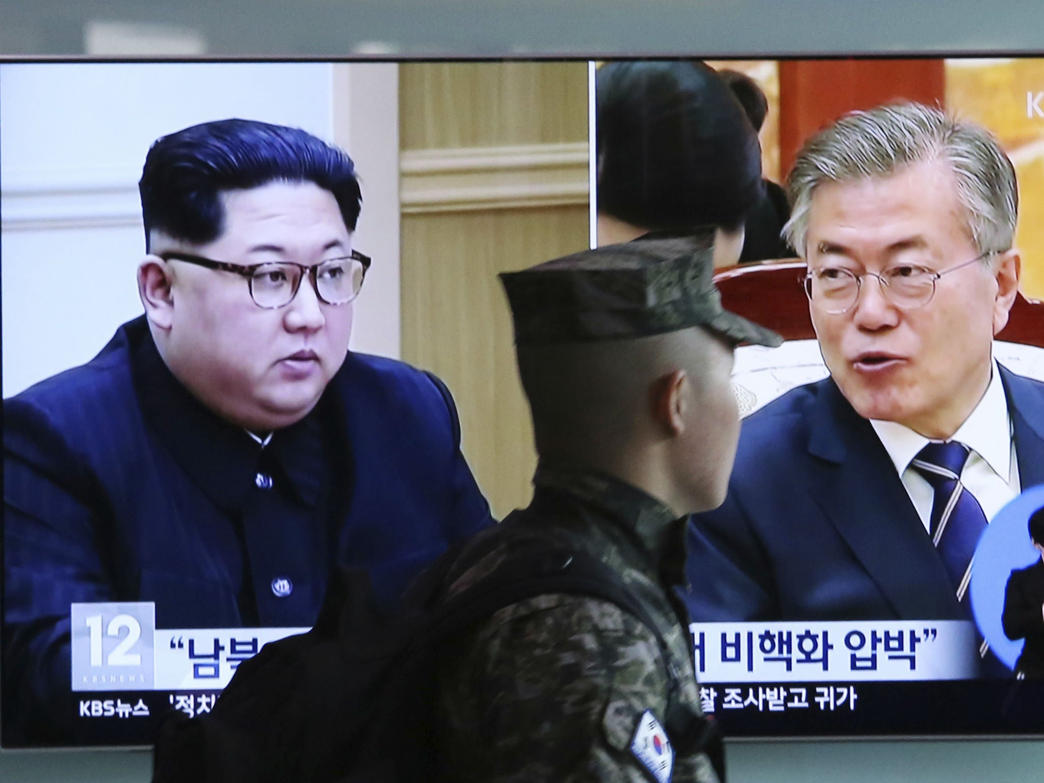 A South Korean soldier passes by a TV screen showing Korean President Moon Jae-in and North Korean leader Kim Jong-un in Seoul, South Korea