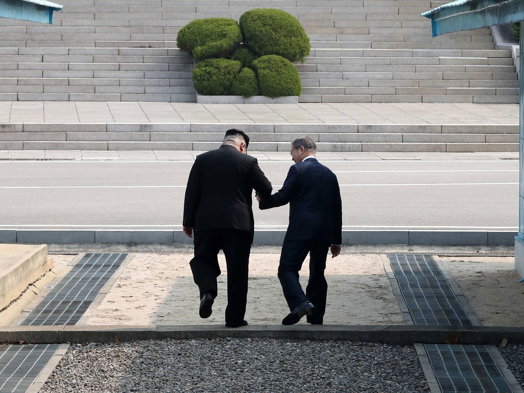 South Korean President Moon Jae-in and North Korean leader Kim Jong-un hold hands as they cross the military demarcation line