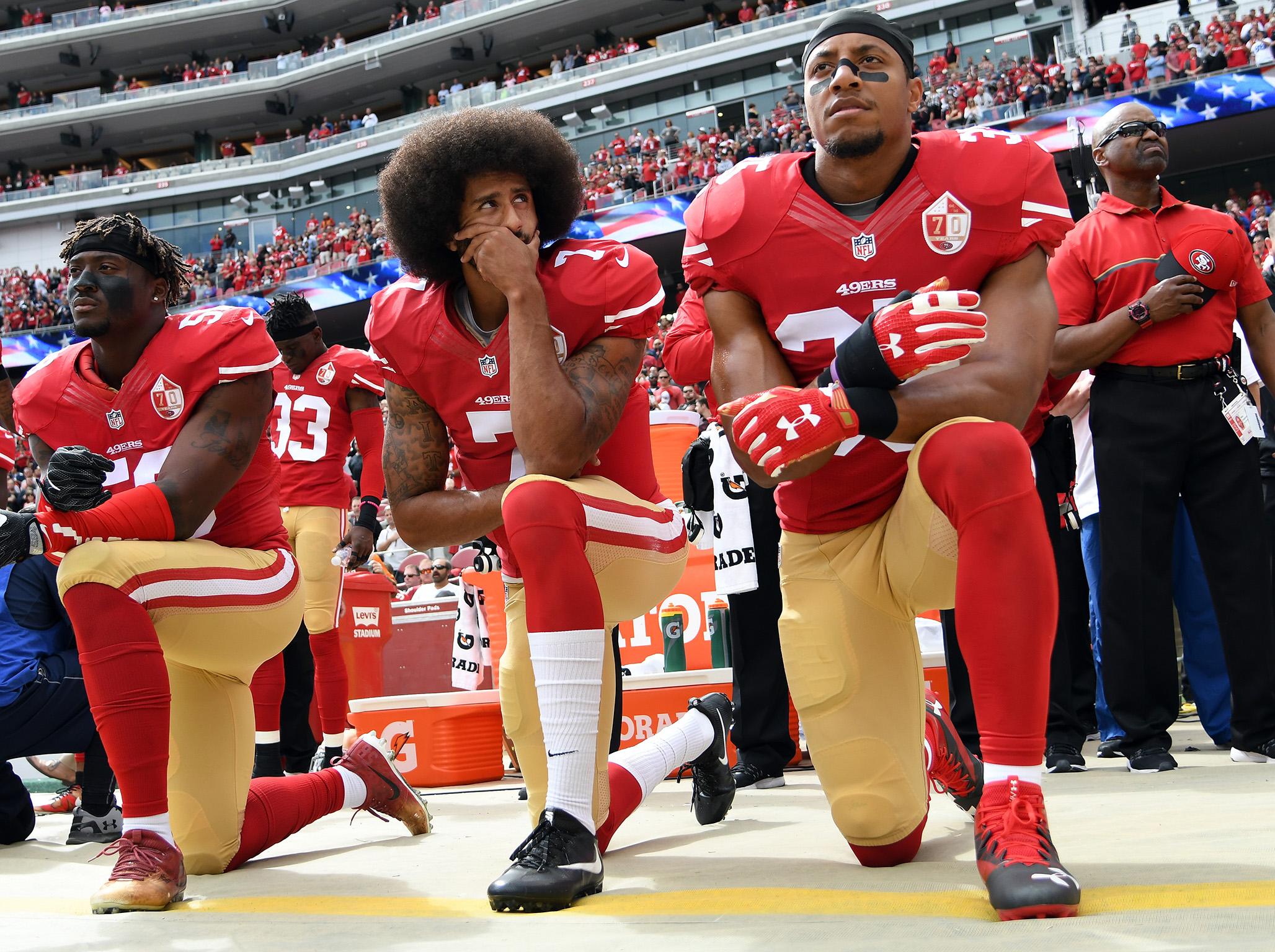 Eric Reid, right, kneels alongside Colin Kaepernick and Eli Harold