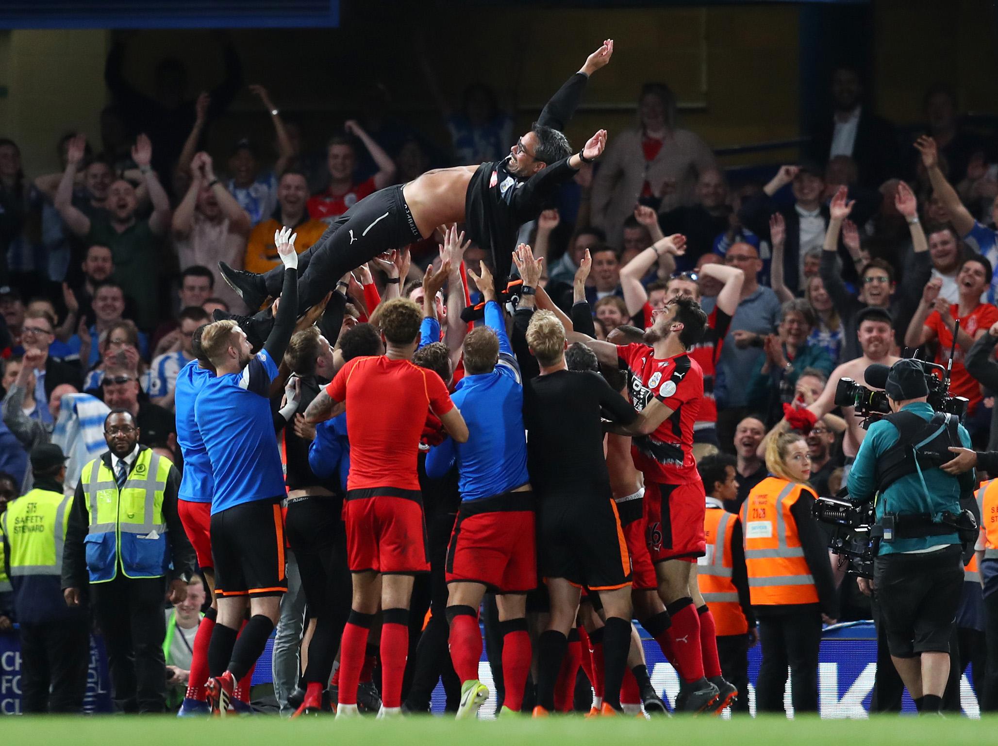 David Wagner is thrown in the air by his players