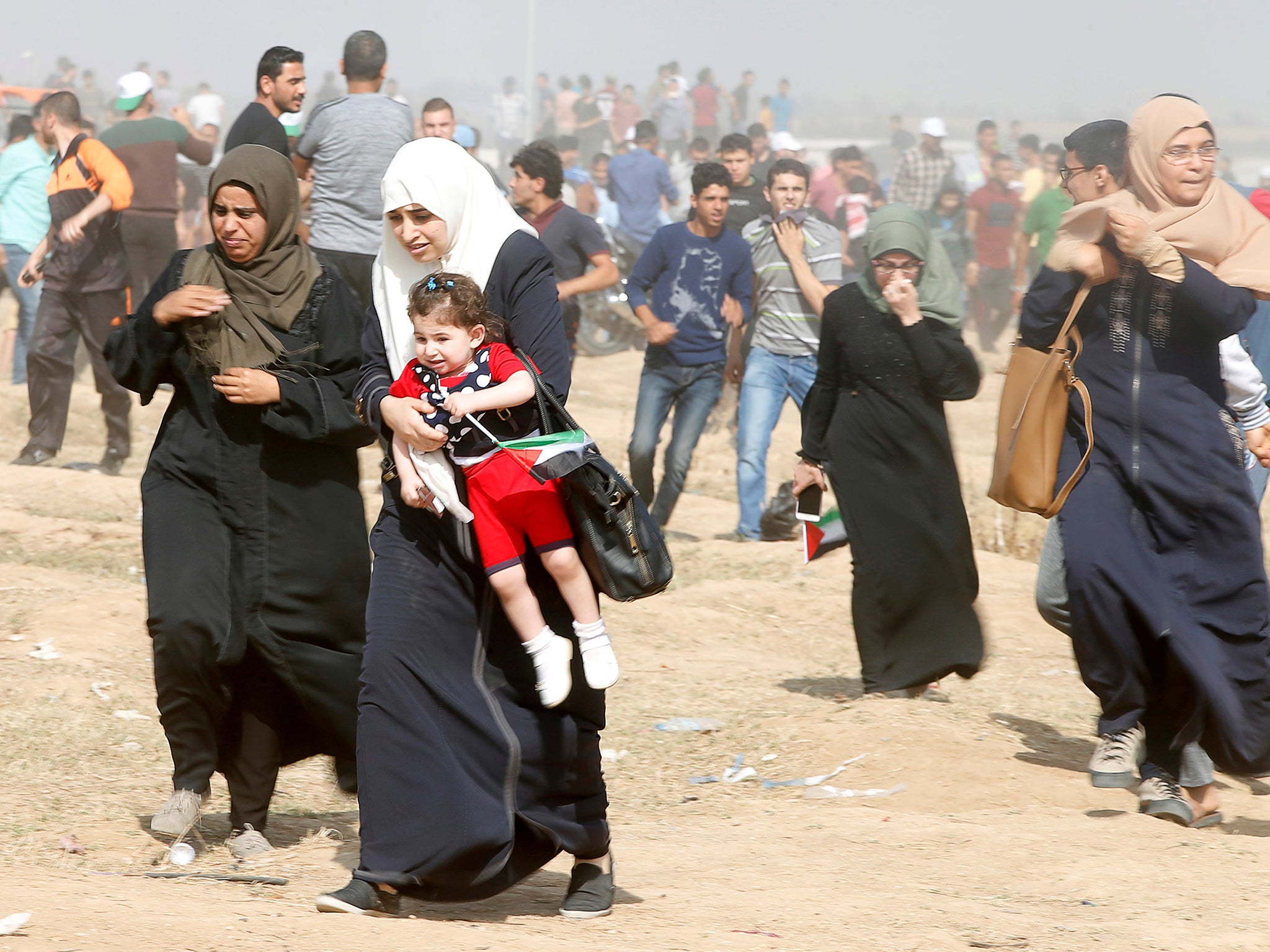 Female Palestinian demonstrators react to tear gas fired by Israeli forces