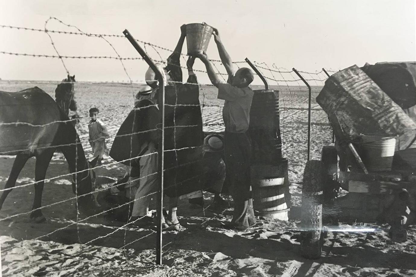 Arabs from the village of Huj pass a bucket of water to the newly arrived Jewish settlers at the kibbutz of Dorot, circa 1942. Huj was destroyed in 1948