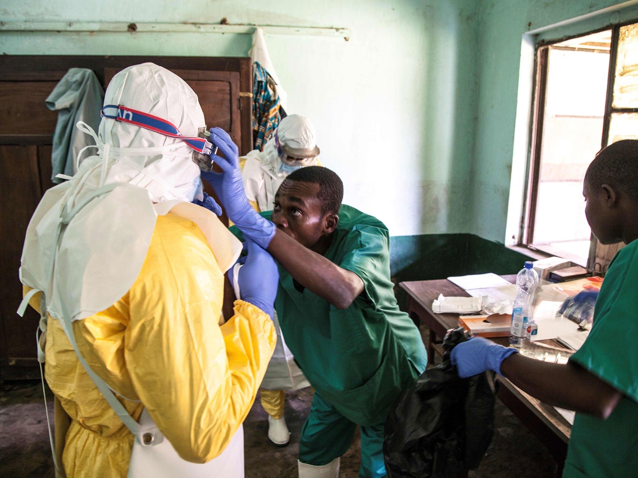 Health workers wear protective equipment as they prepare to attend to suspected Ebola patients