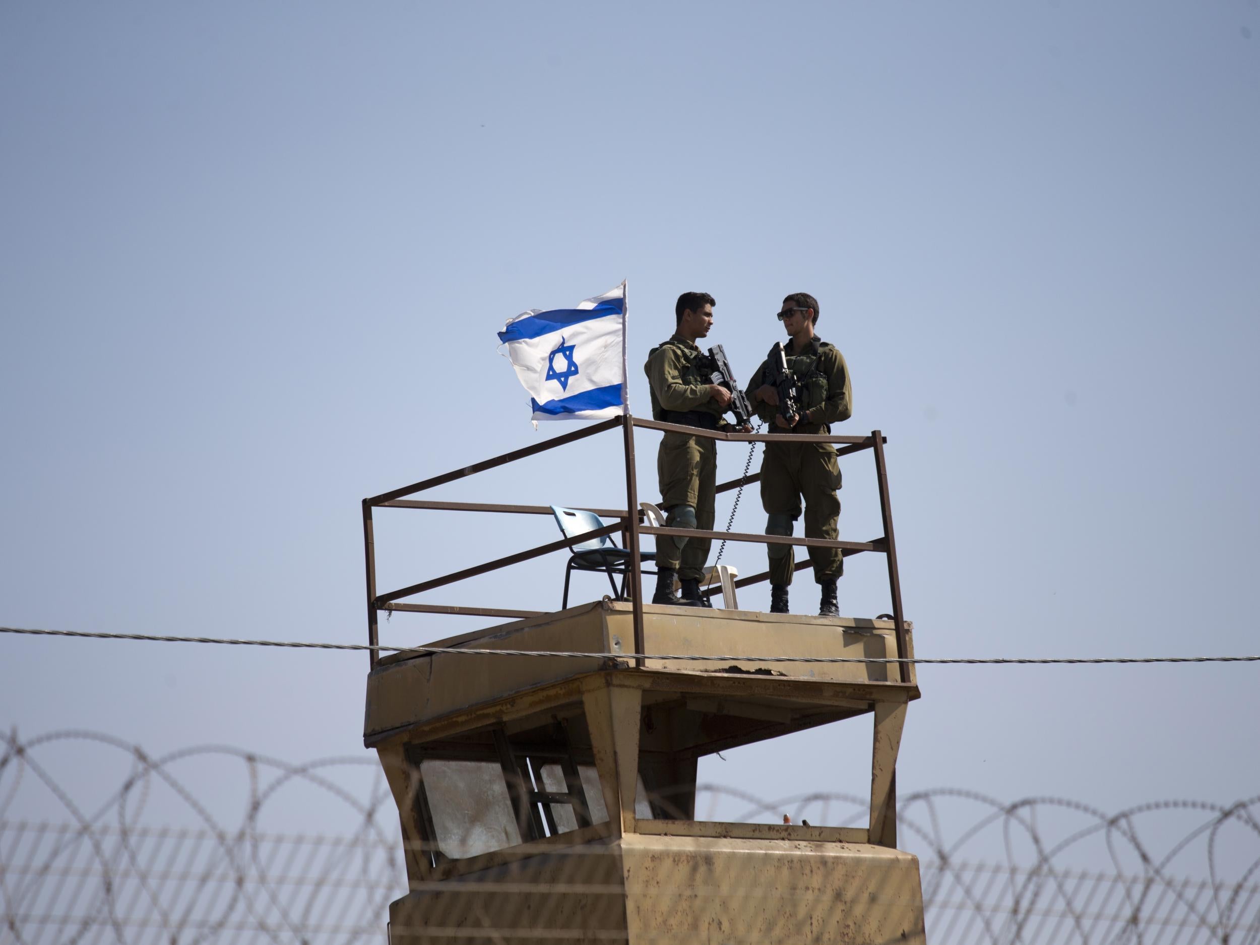 Israeli soldiers guard on top of a watch tower along the Israel-Gaza border