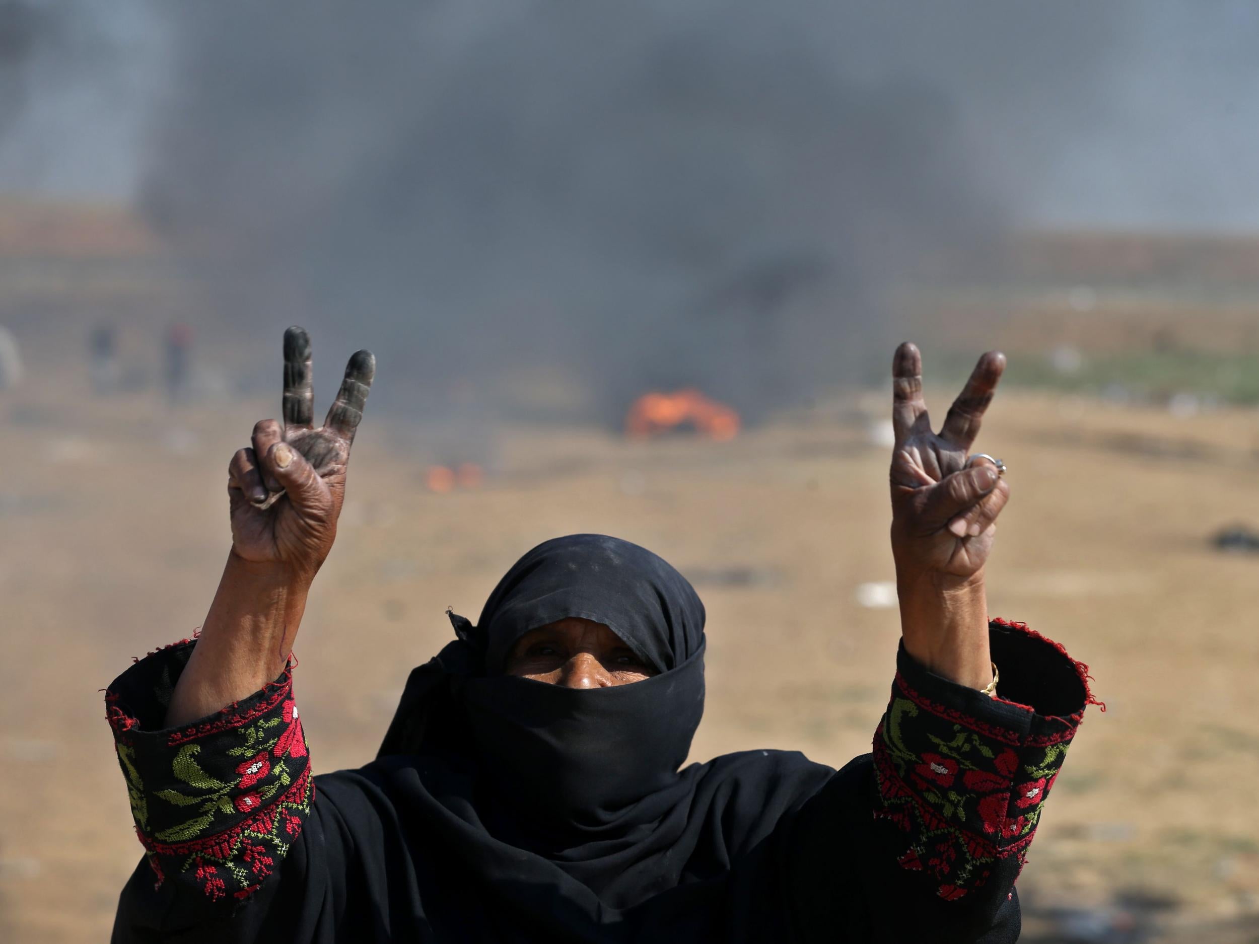 A Palestinian woman flashes the V for victory sign during protest near the border fence on 15 May