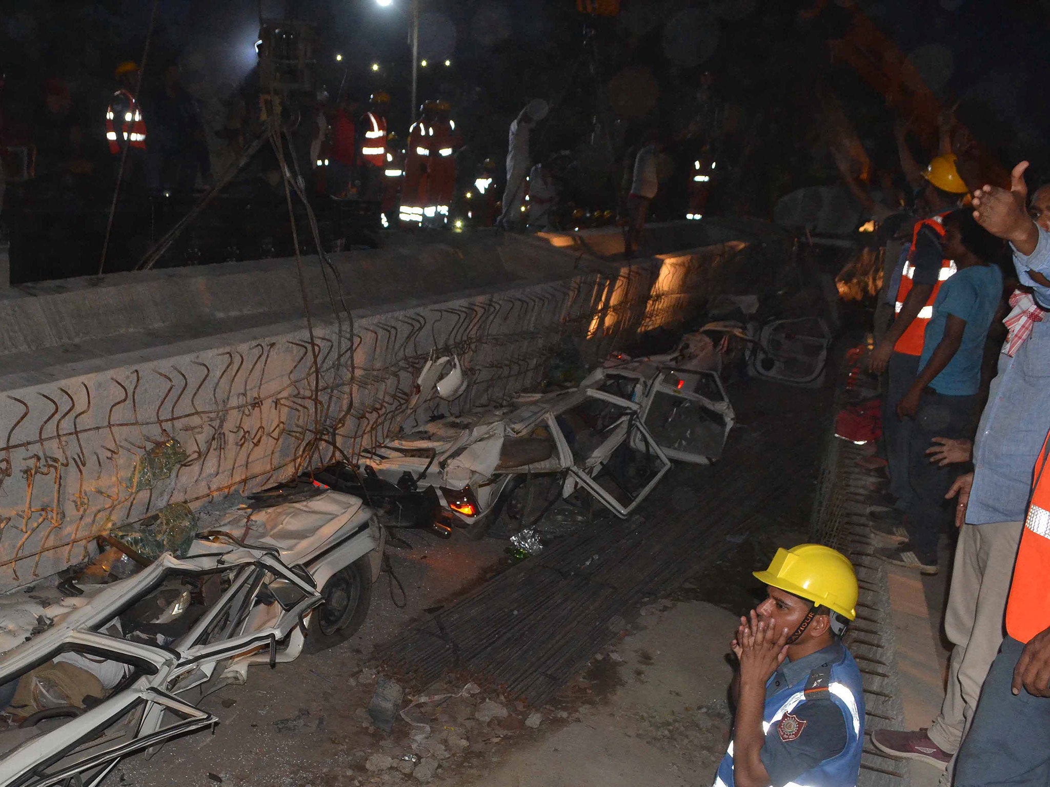 Rescue workers prepare to remove a beam as vehicles are seen trapped under the rubble after a part of an under construction flyover collapsed in Varanasi, India