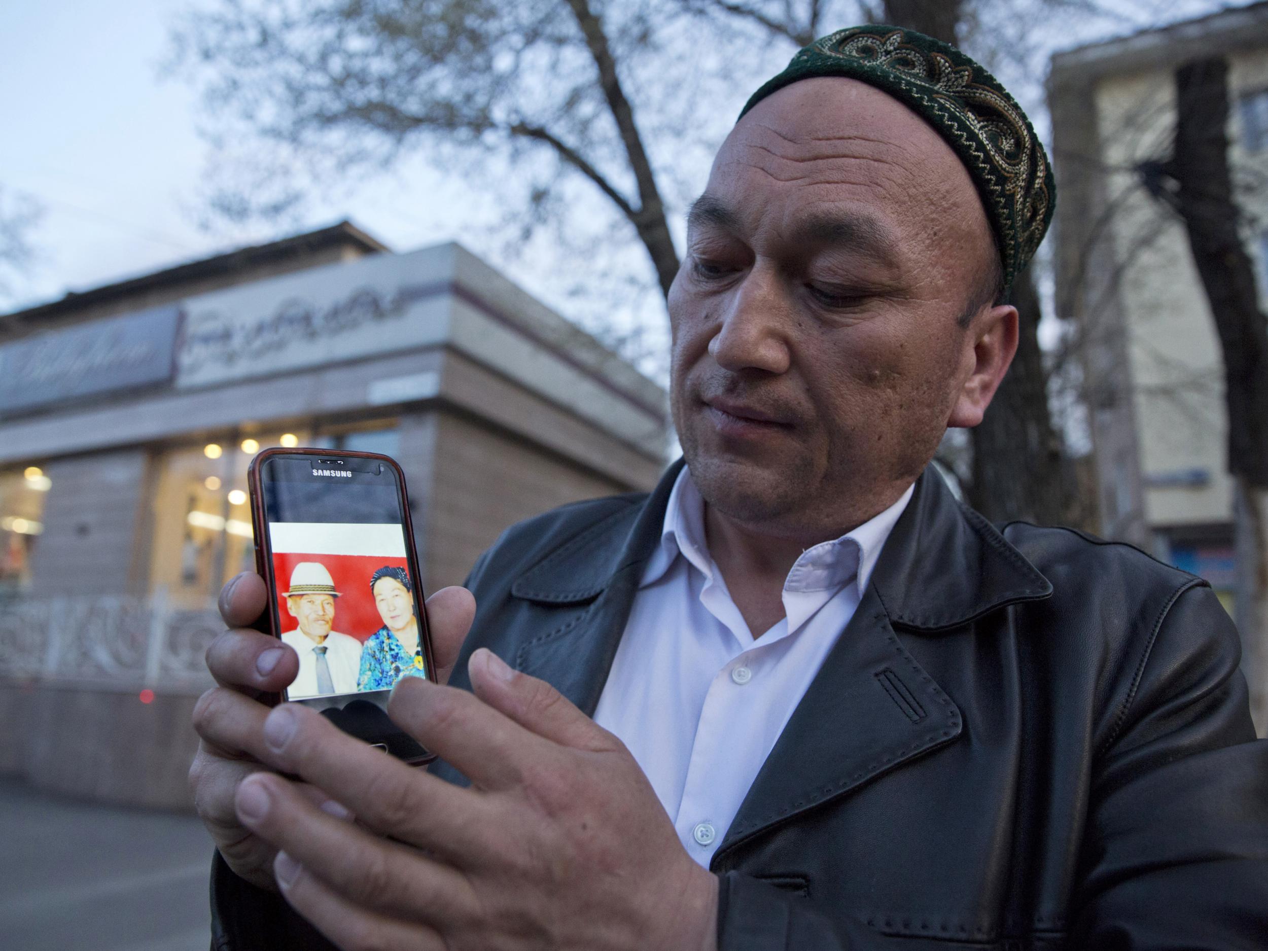 Omir Bekali displays a photo of his parents who he believes have now been interned in China