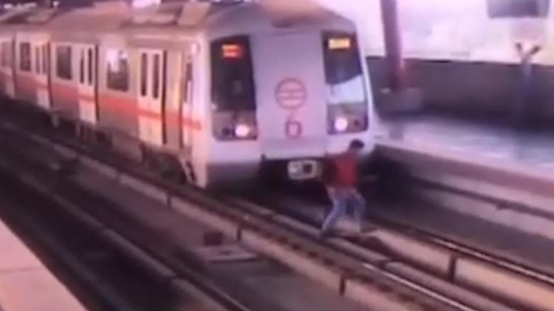 CCTV shows passenger walking across tracks in front of train on metro