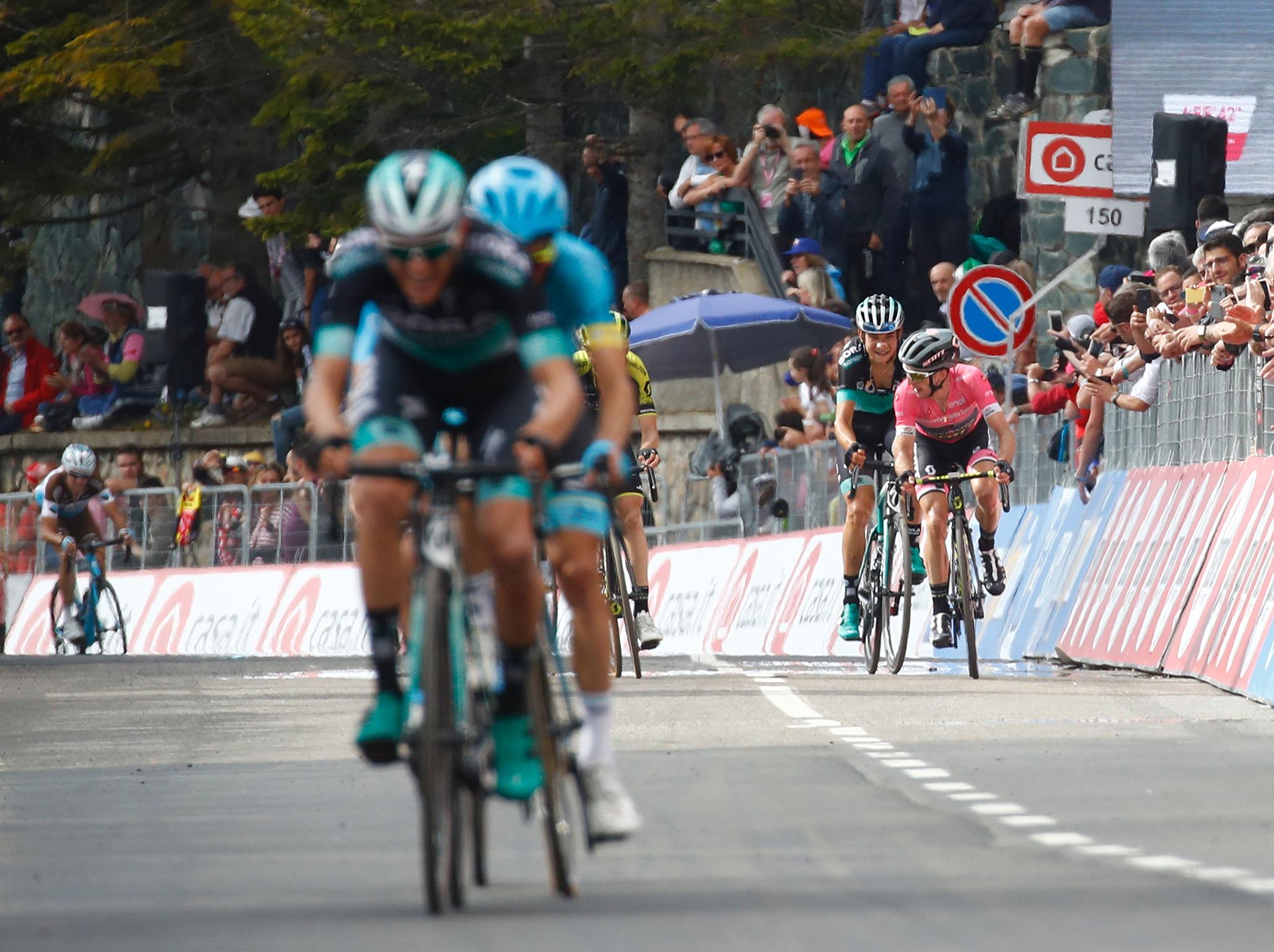 Simon Yates in pink reaches the finish at Prato Nevoso