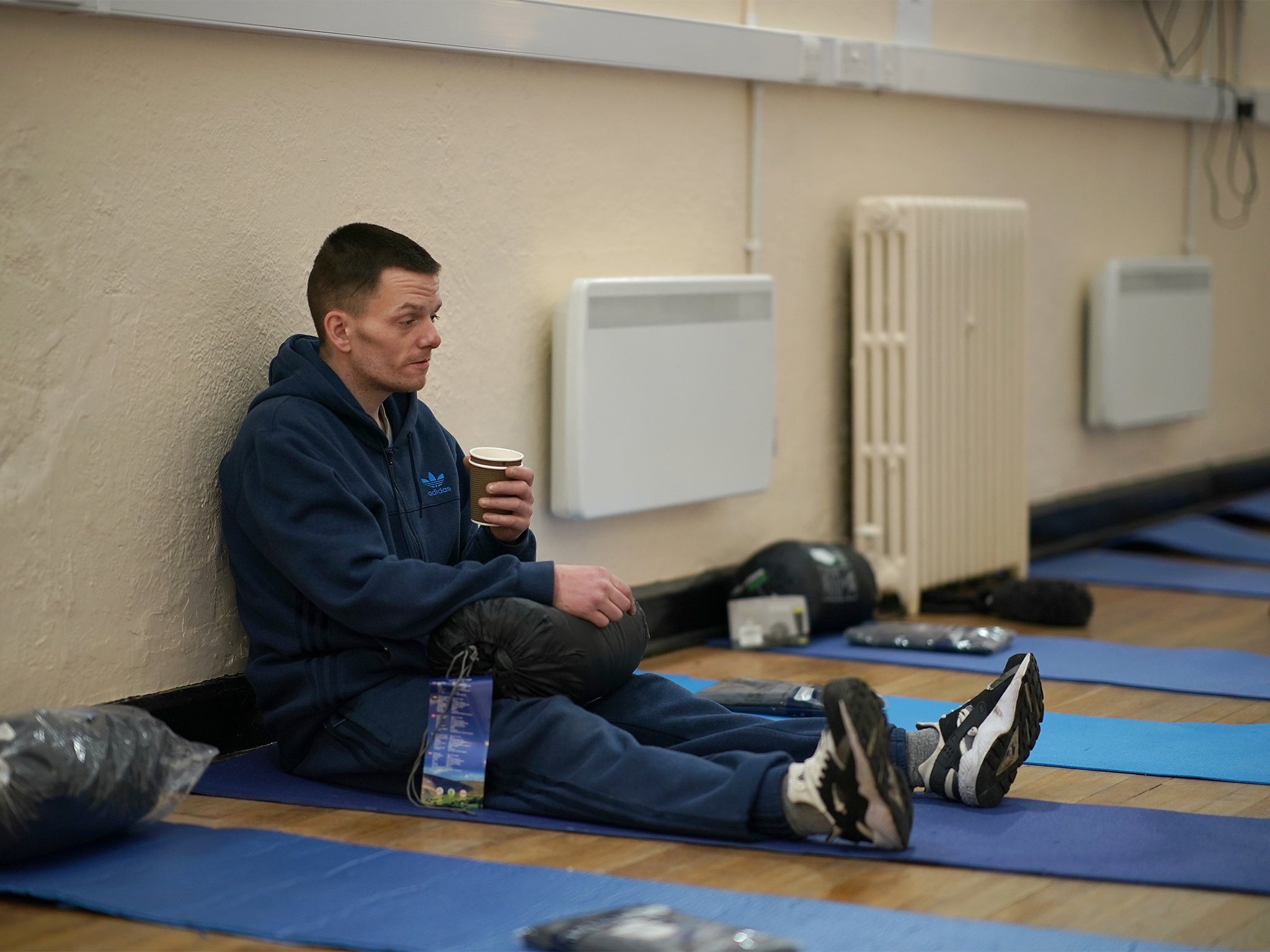 A homeless man sits on a sleeping mat in Liverpool’s Labre House rough sleepers shelter (Getty)