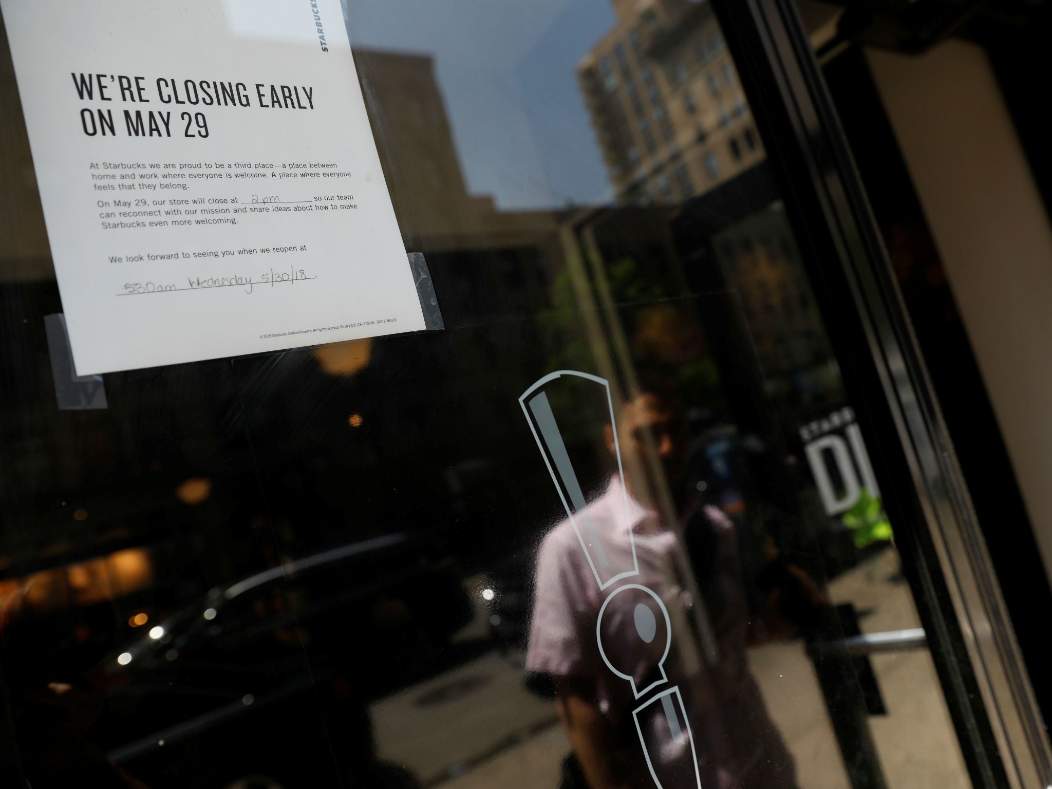 A sign in the window of a door of a Starbucks explains the store will close early for racial bias training