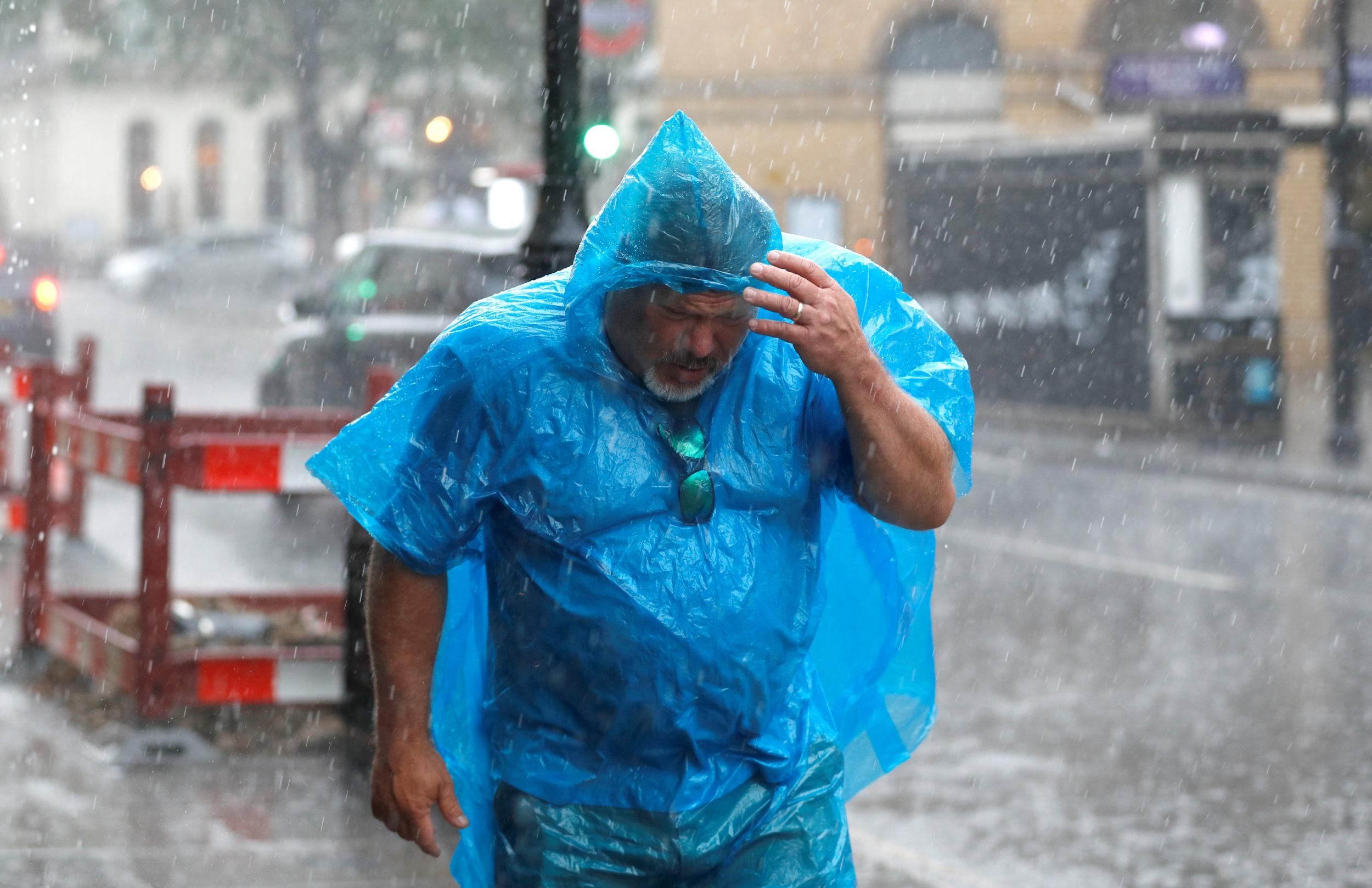 A man shelters as best he can from the heavy rain in central London