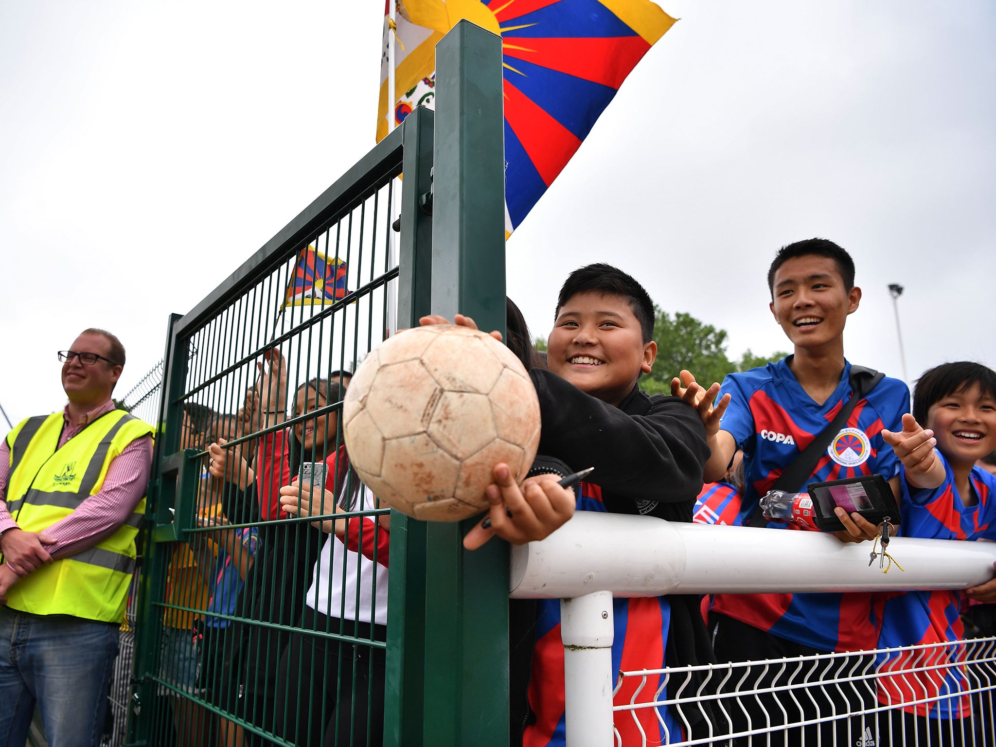 A young Tibet fan holds a football in the hope a player will sign it