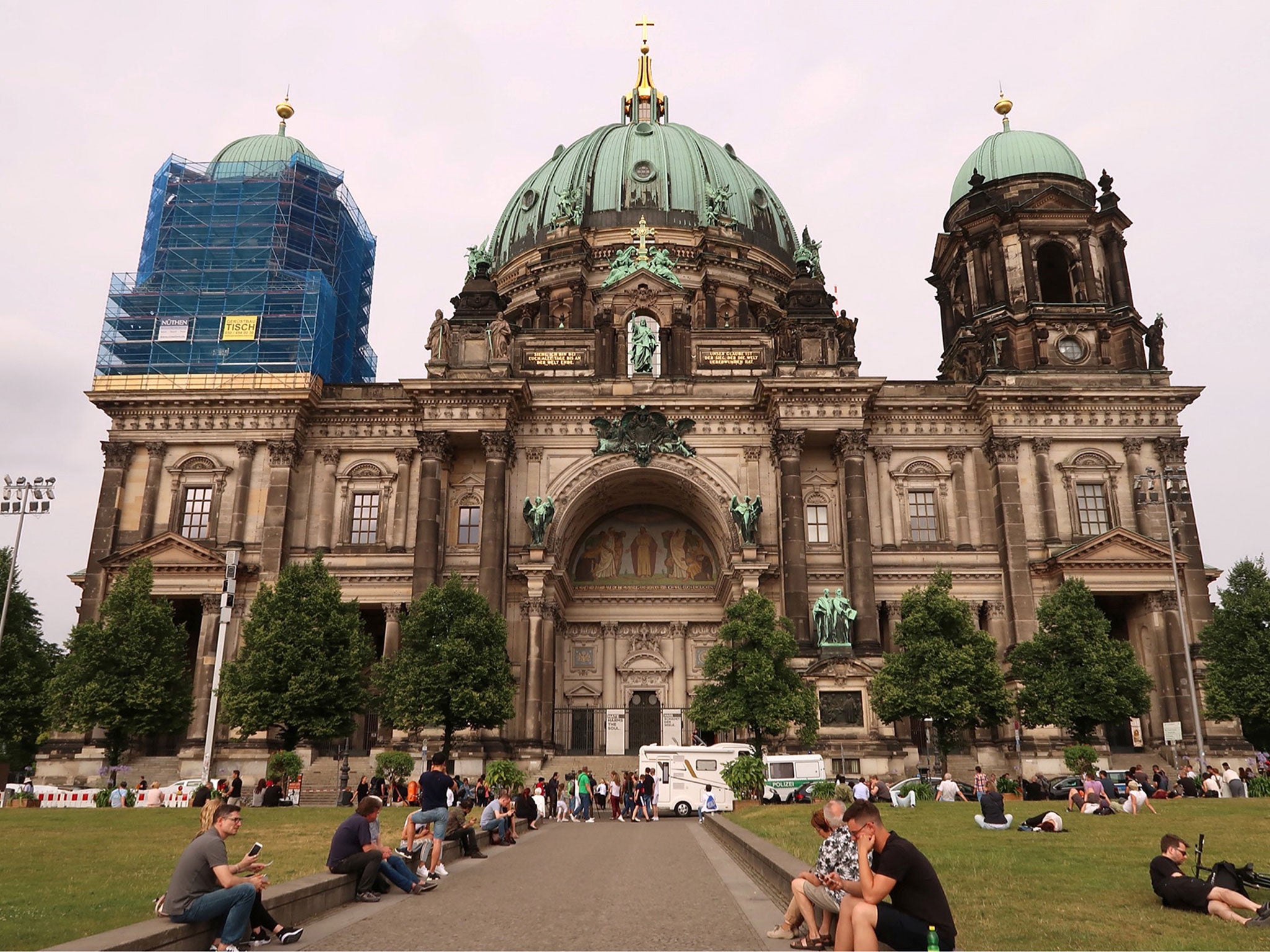 People sit in front of the Berliner Dom after a German policeman shot a man at the Berlin Cathedral