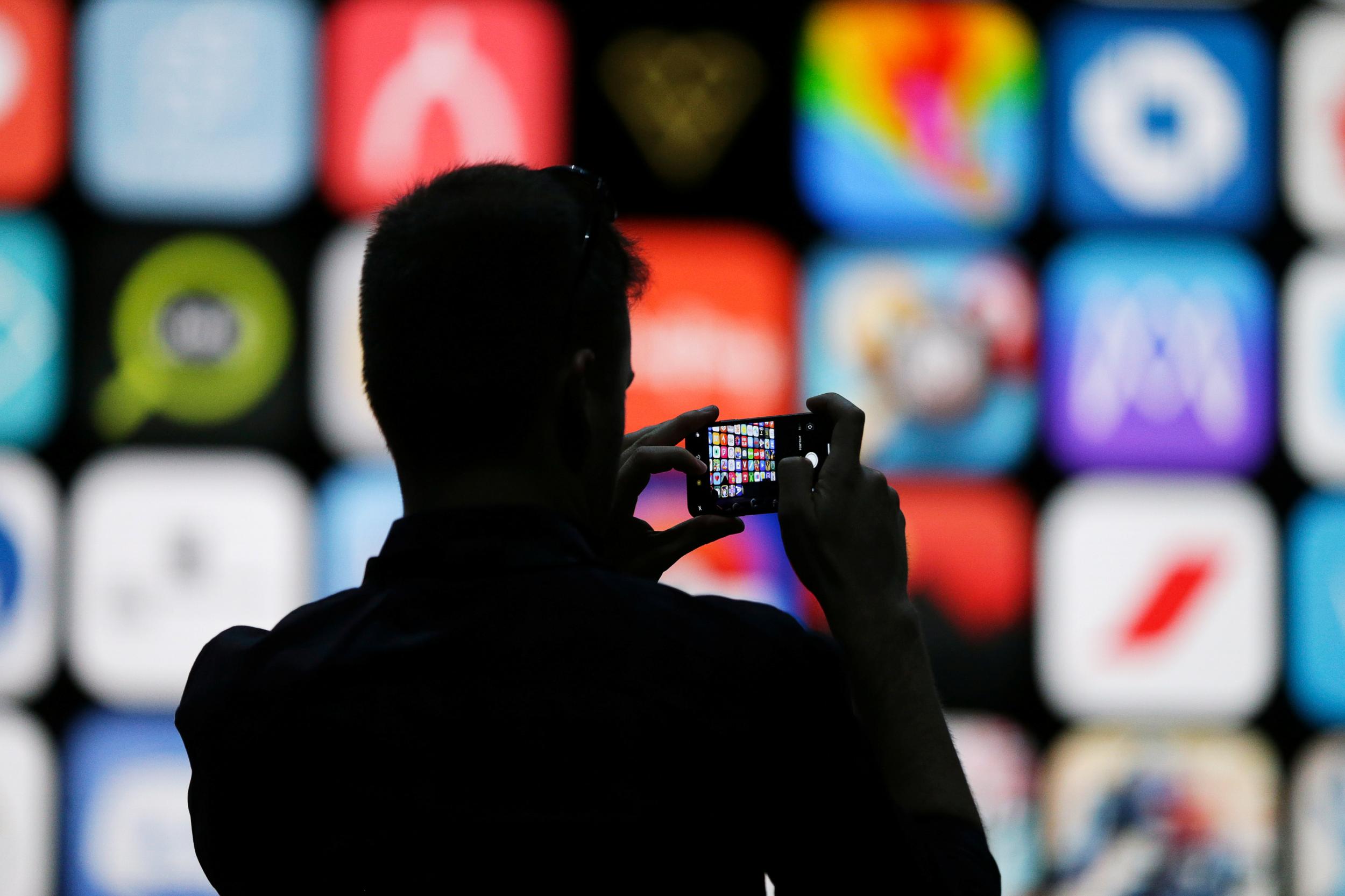 A visitor uses his iPhone X to take photos of the stage at the Apple Worldwide Developer conference in San Jose, California, U.S., June 4, 2018