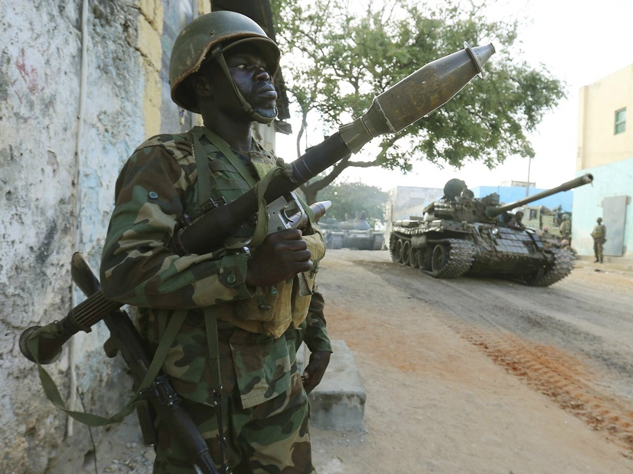 A Somali army soldier keeps guard as a tank rolls past after they captured the town of Barawe in 2014. The US military helps local forces to fight terror group al Shabaab