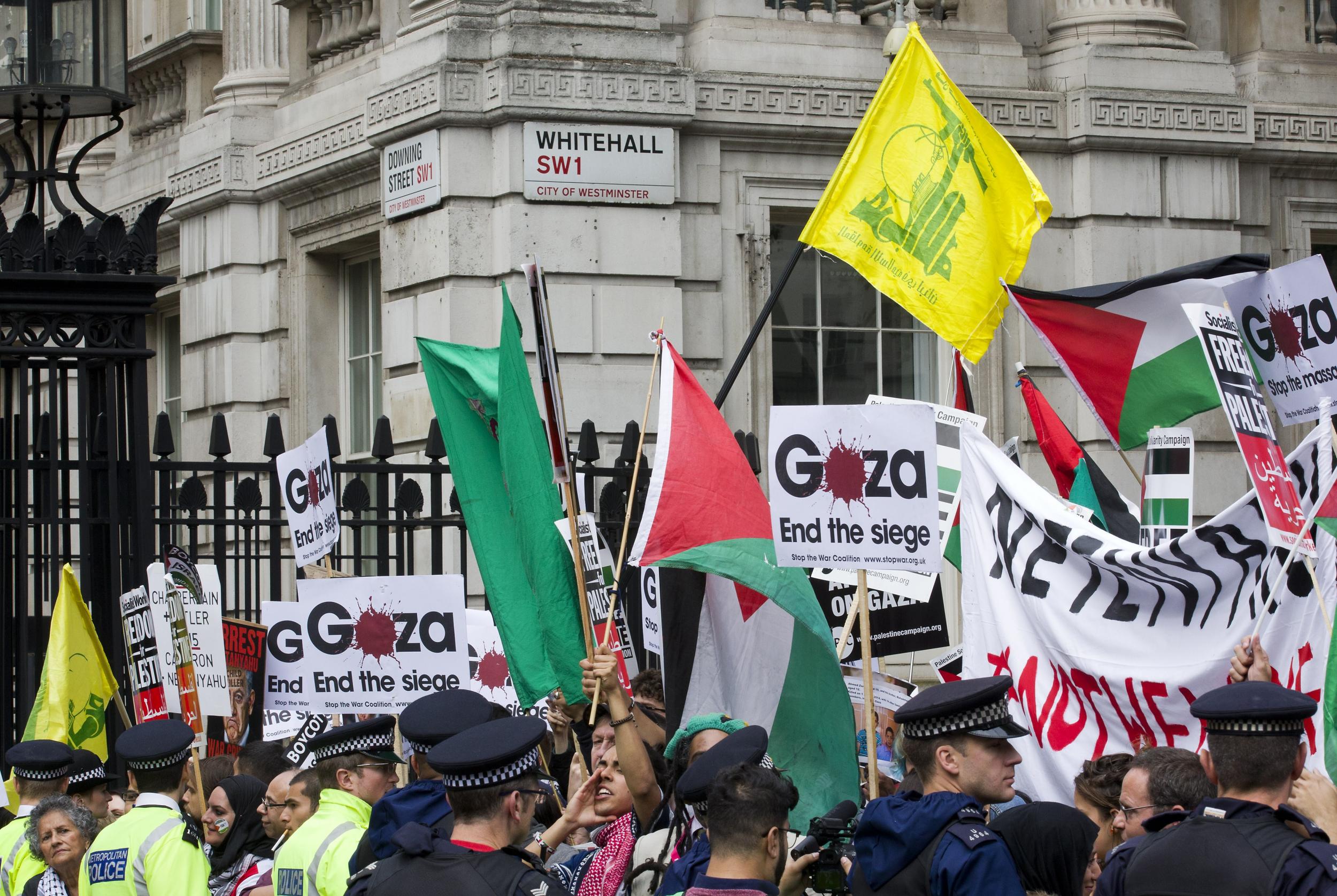 Pro-Palestinian demonstrators carry the yellow flag of Lebanese Shia group, even though our government has proscribed their militant wing