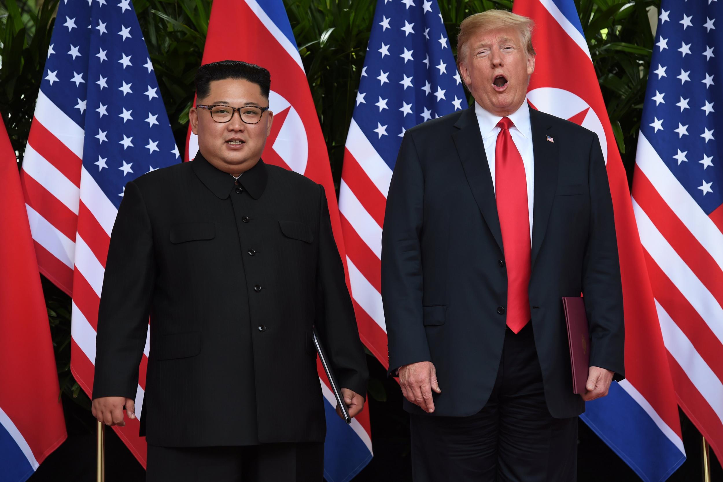 Donald Trump and North Korea's leader Kim Jong-un react during their summit at the Capella Hotel