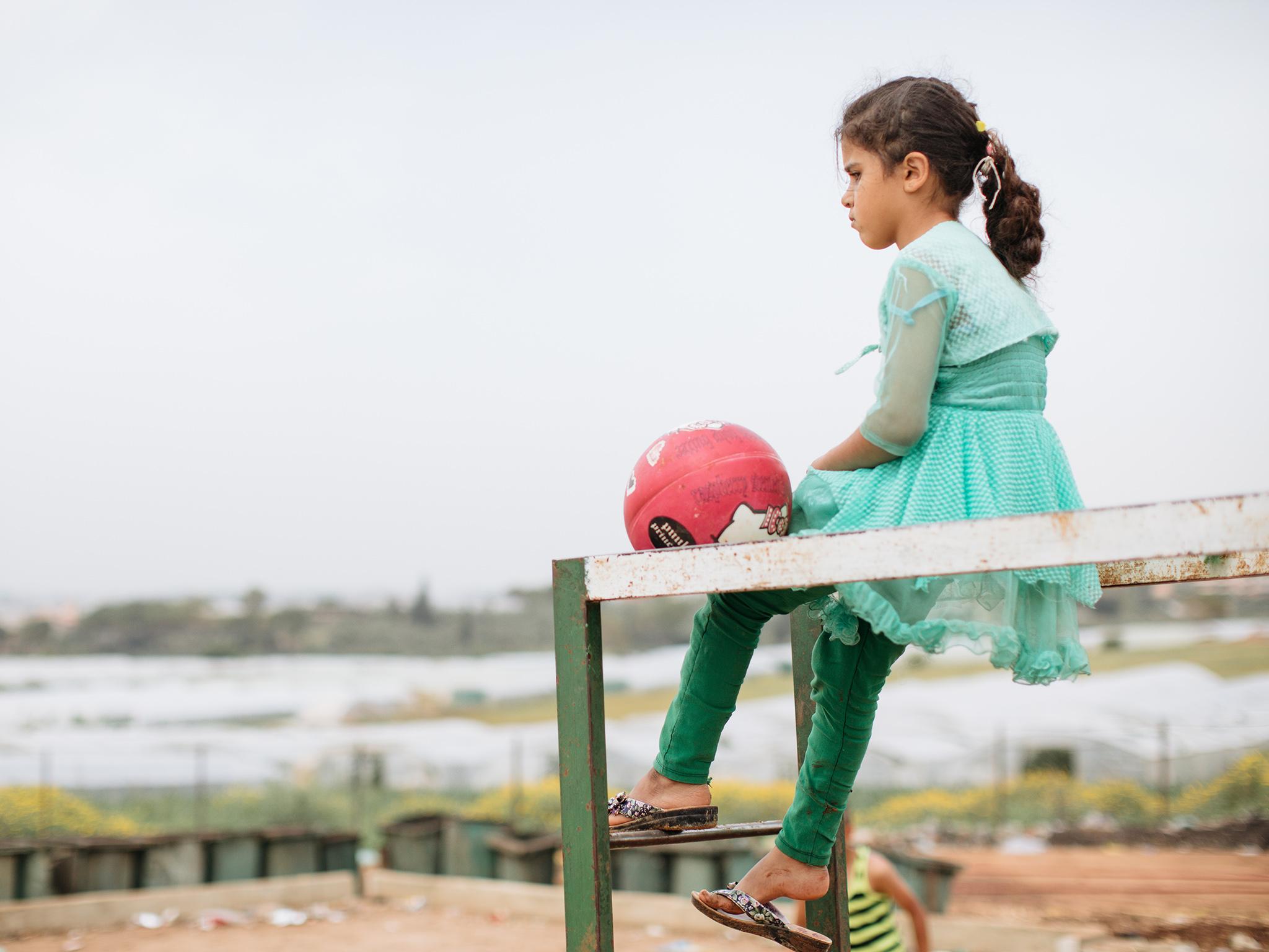 A girl looks out across the Enmaa Camp. The 250 tents have been squeezed onto a small plot of land amongst a smart residential neighbourhood and acres of poly tunnels growing fruit and vegetables