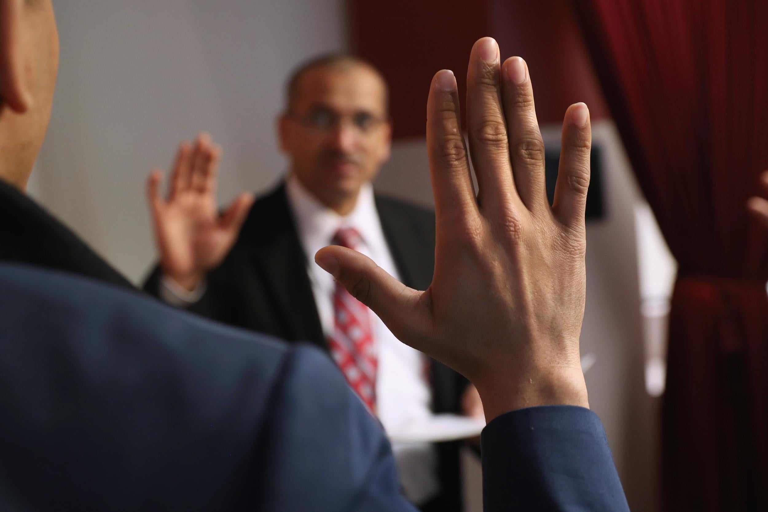 An immigration supervisor swears in new American citizens at a naturalization ceremony