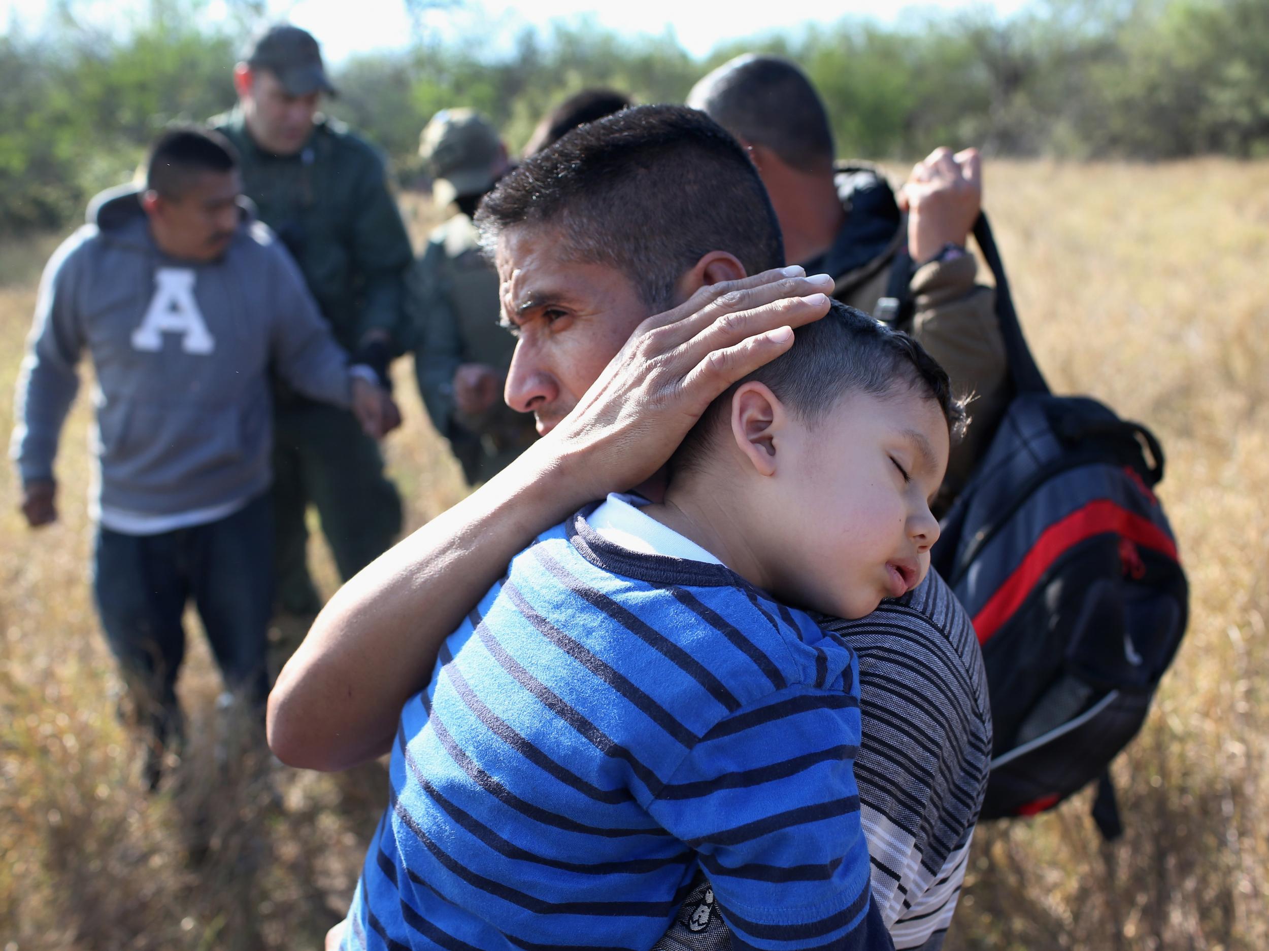 A father holds his sleeping three-year-old son, 3, after they were detained by Border Patrol agents near Rio Grande City, Texas