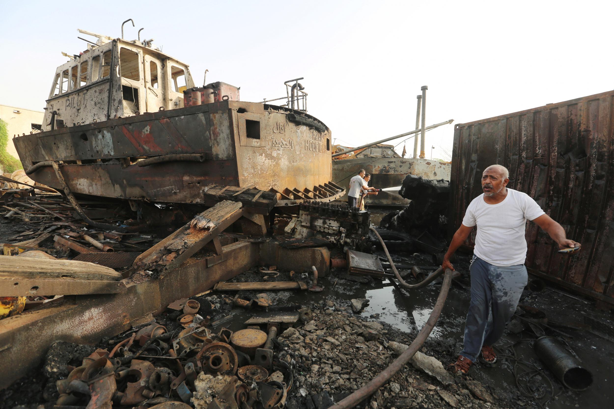 Workers inspect damage at the site of an airstrike on the maintenance hub at Hodeidah's port on 27 May 2018