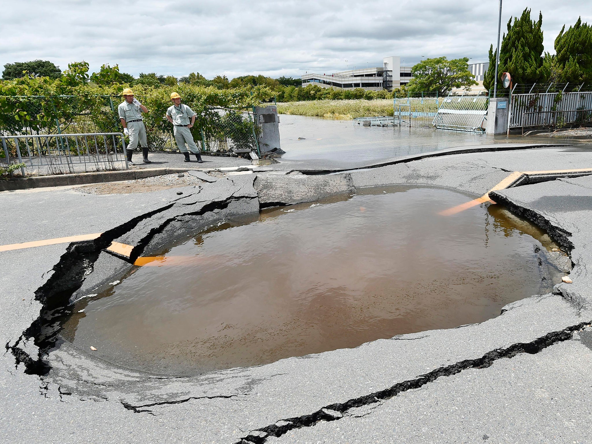 A crack is filled with water on a road after water pipes were broken following an earthquake in Takatsuki city, Osaka, western Japan, Monday, June 18, 2018. A strong earthquake knocked over walls and set off scattered fires around metropolitan Osaka on Monday morning. (Keiji Uesho/Kyodo News via AP)