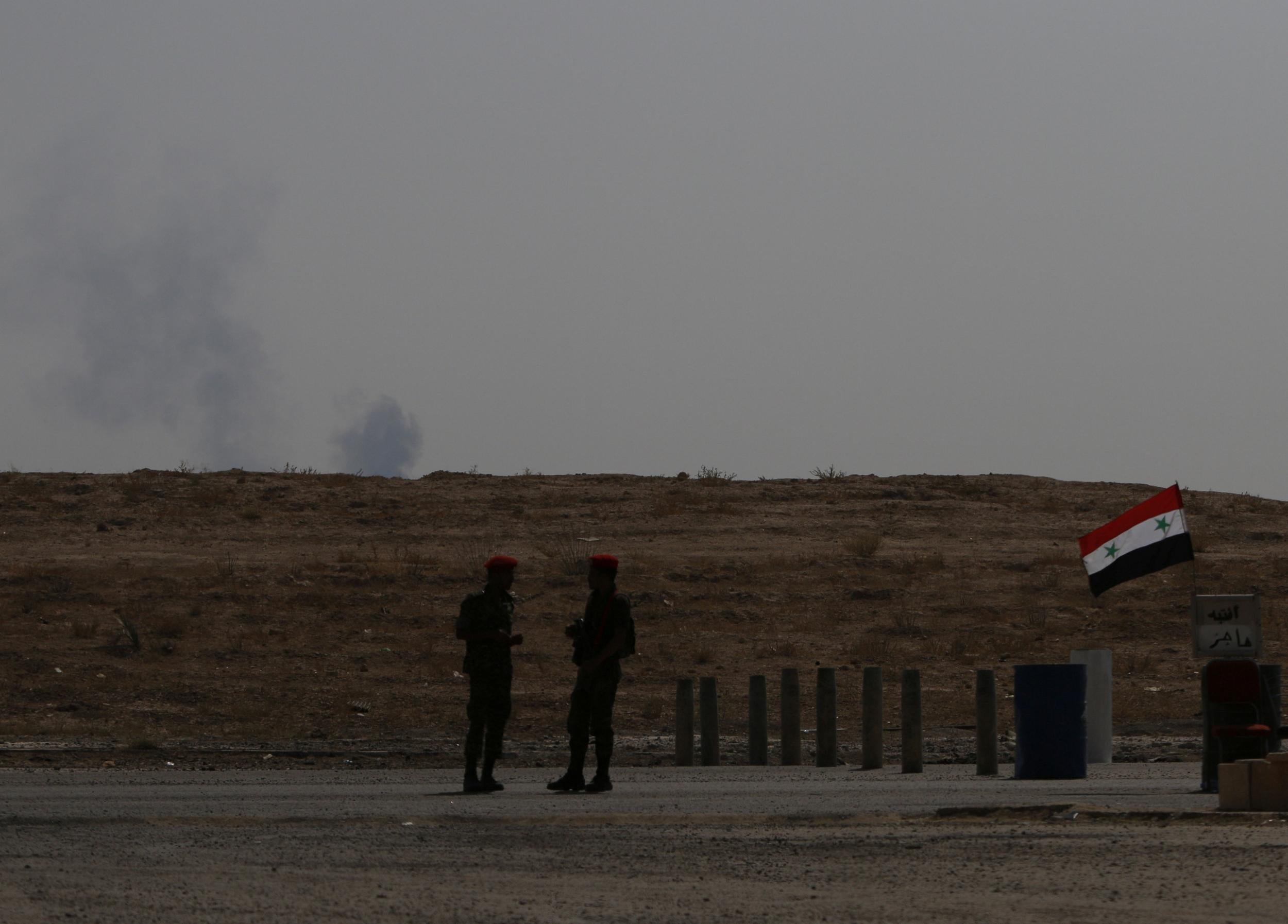 Smoke rises as Syrian army soldiers stand near a checkpoint in Deir Ezzor in this file photo from 21 September, 2017