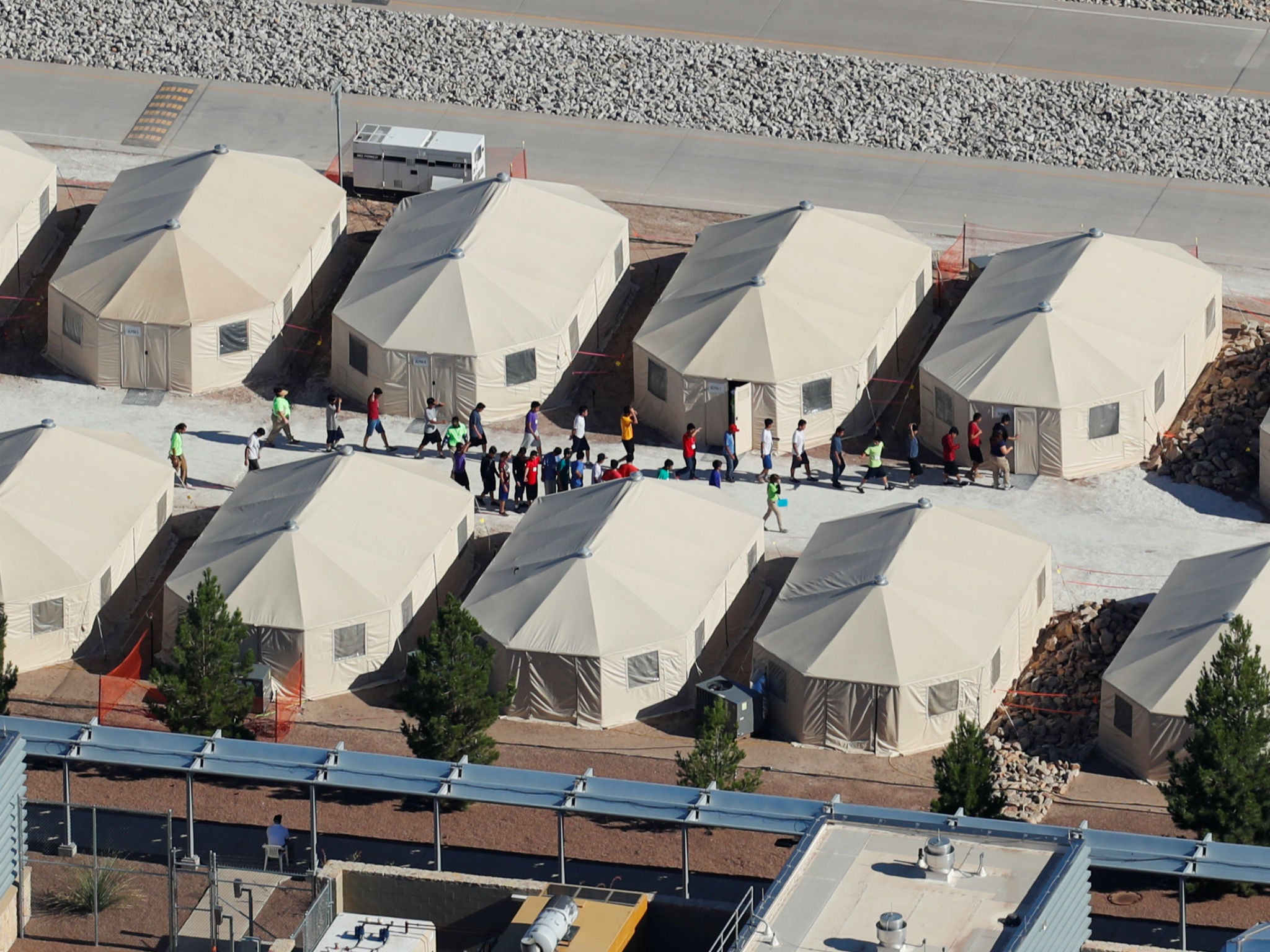 Immigrant children, many of whom have been separated from their parents under a new 'zero tolerance' policy by the Trump administration, are shown walking in single file between tents in their compound next to the Mexican border in Tornillo, Texas