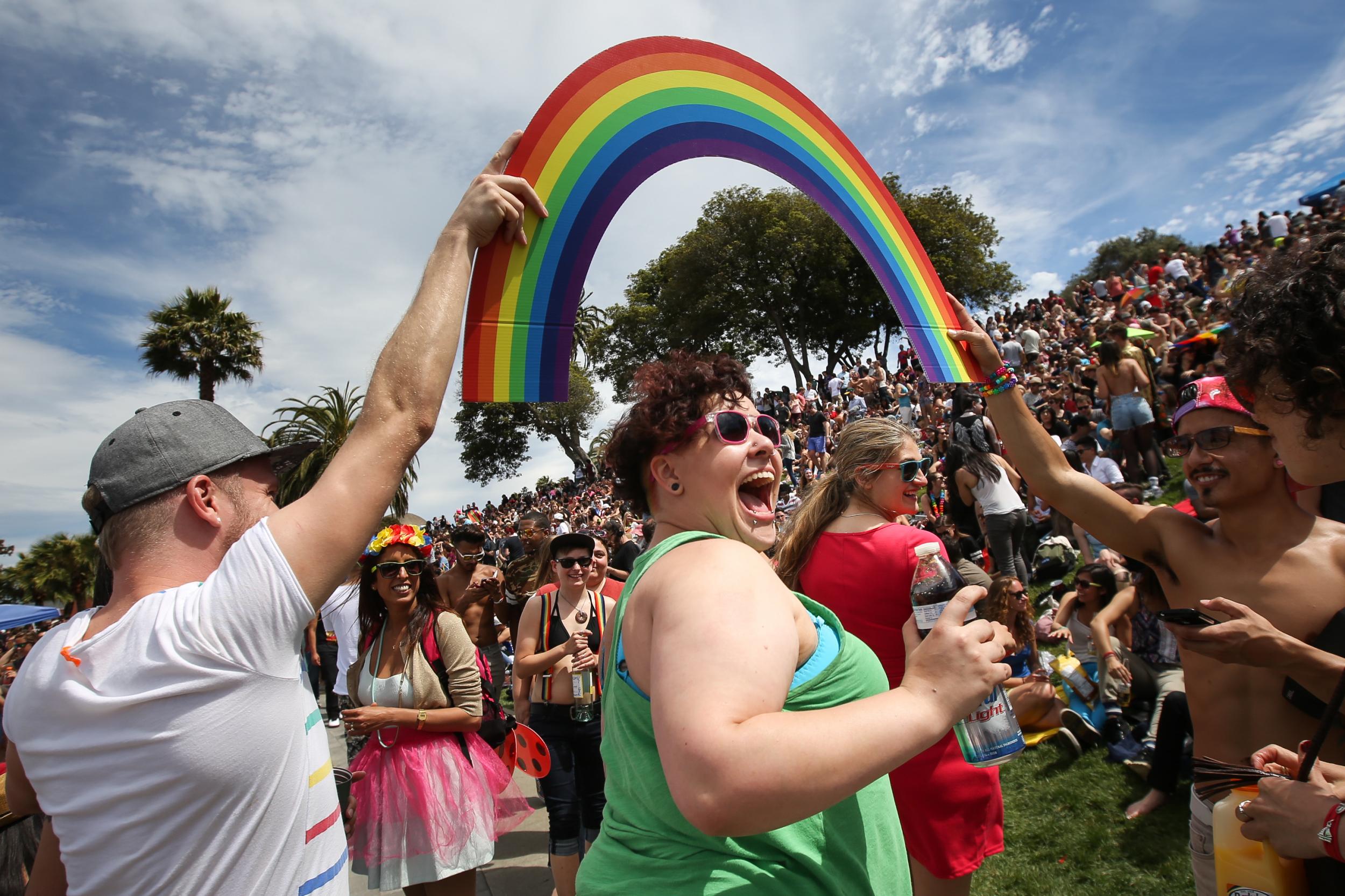 Daniela Lopez smiles as she walks under a rainbow held by two men during a gay pride celebration in Dolores Park on June 27, 2015
