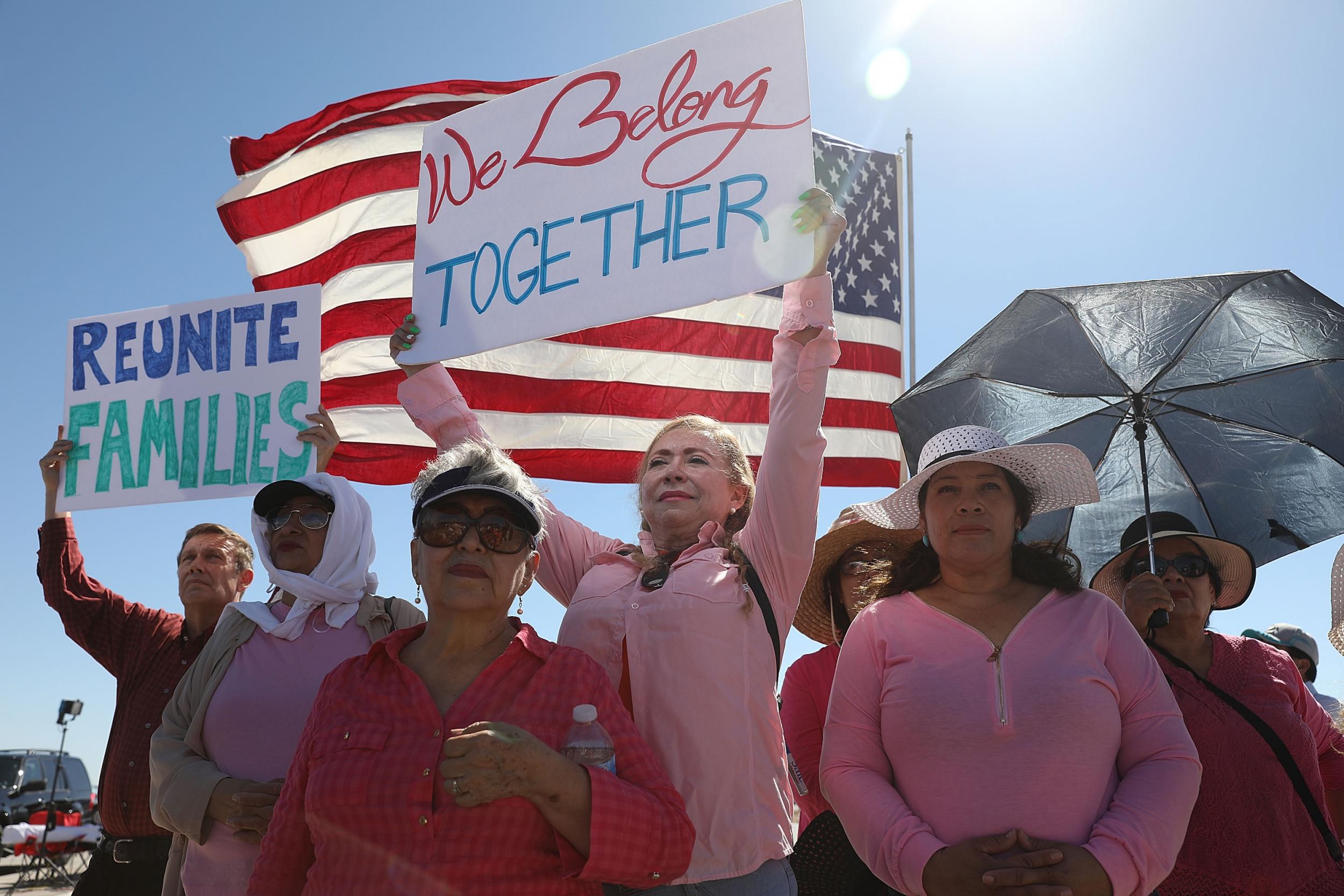 Linda Posada holds up a sign that reads, ' we belong together,' as mayors with the U.S. Conference of Mayors speak call for the immediate reunification of separated immigrant families