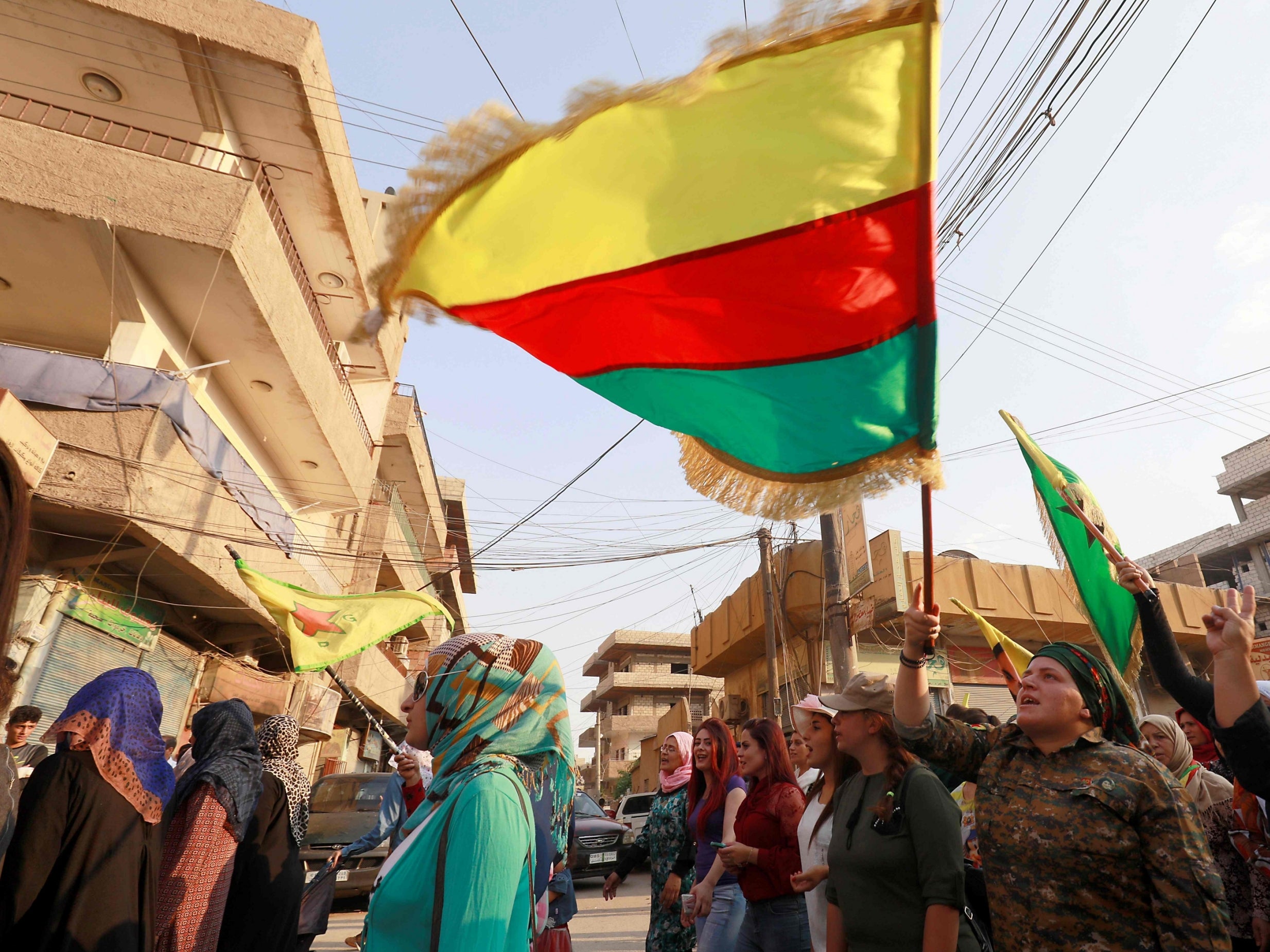 Syrian-Kurdish demonstrators wave Kurdish flags as they protest against demographic changes forced by Turkey to repopulate Kurdish areas, in Qamishli on June 23, 2018.