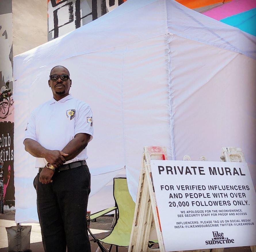 A security guard in front of the covered mural