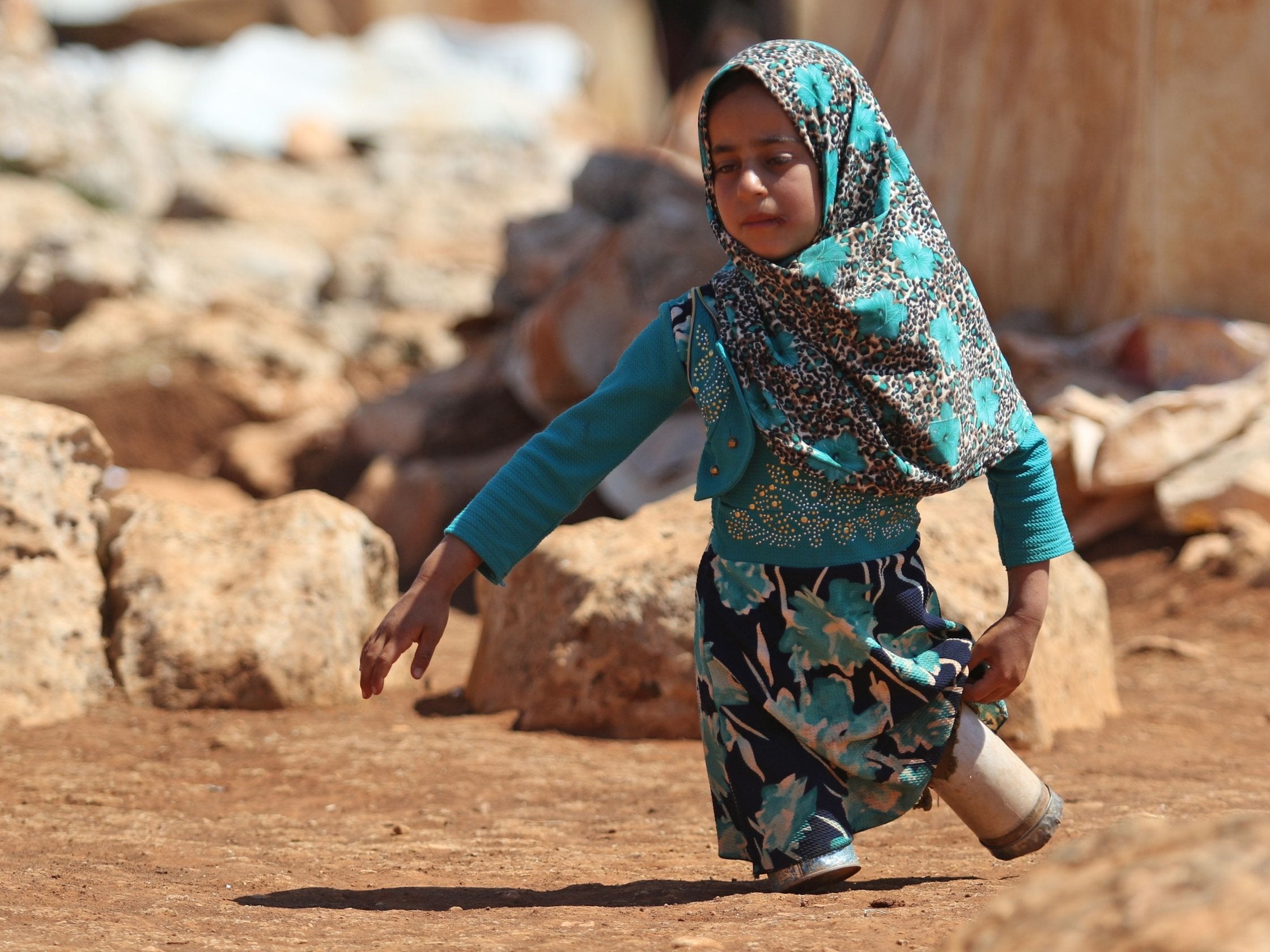 Maya in the refugee camp, walking with legs made of tin cans