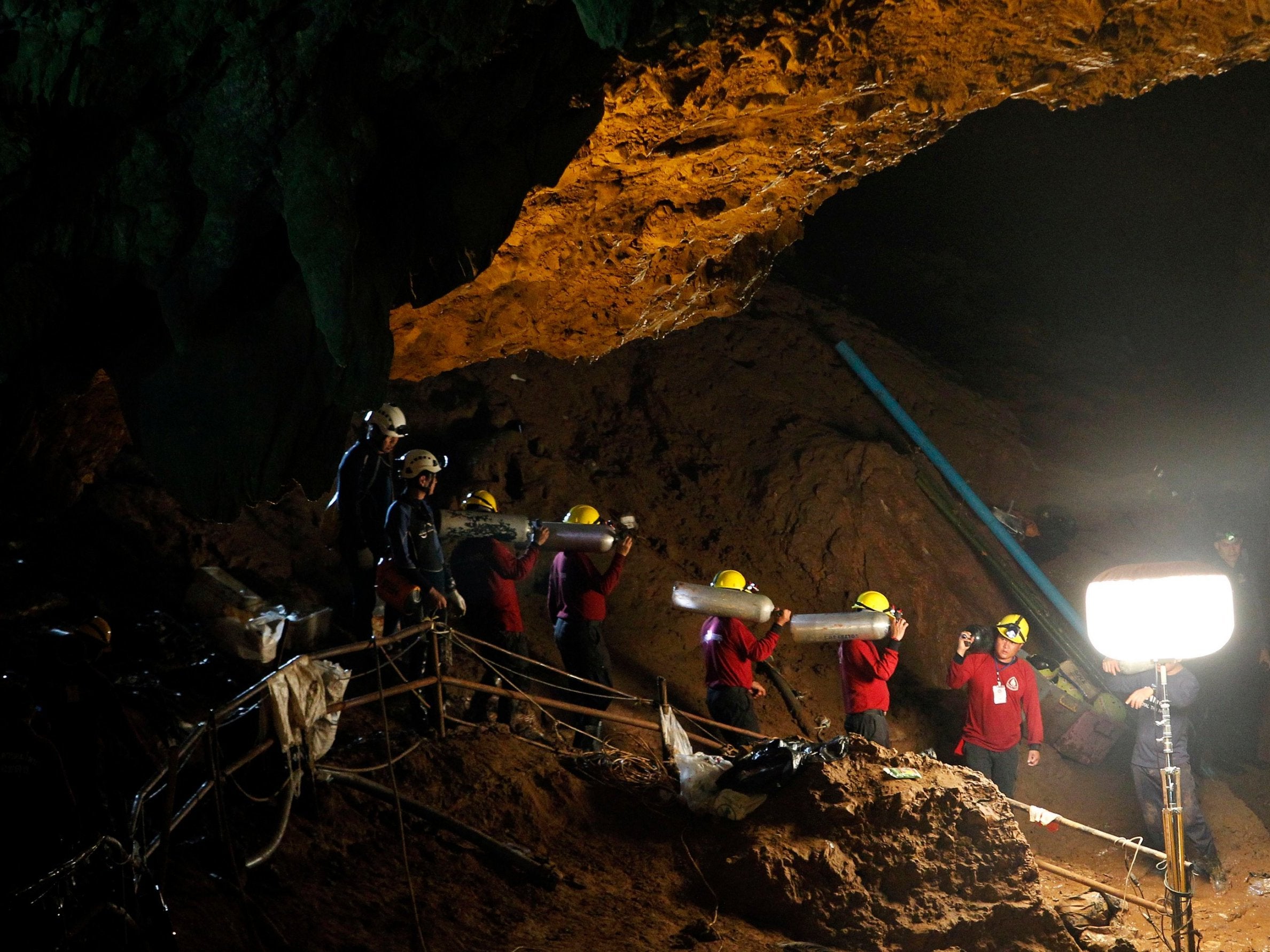 Rescuers carry oxygen tanks through the cave complex during a rescue operation