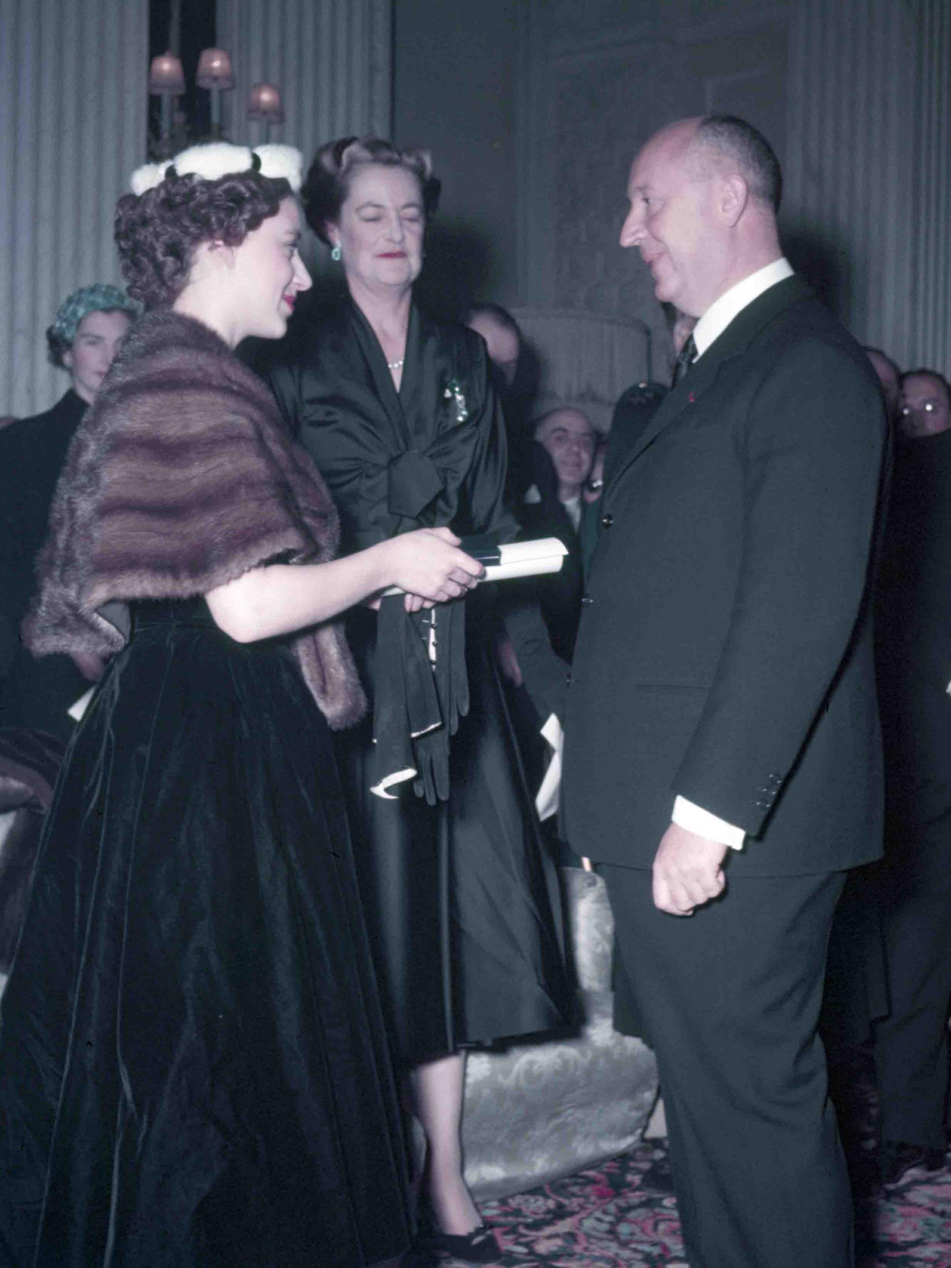 Princess Margaret (left), with the Duchess of Marlborough behind, presents Christian Dior with a scroll entitling him to Honorary Life Membership of the British Red Cross after the presentation of his Winter Collection at Blenheim Palace on 3rd November 1954 (© Popperfoto / Getty Images)