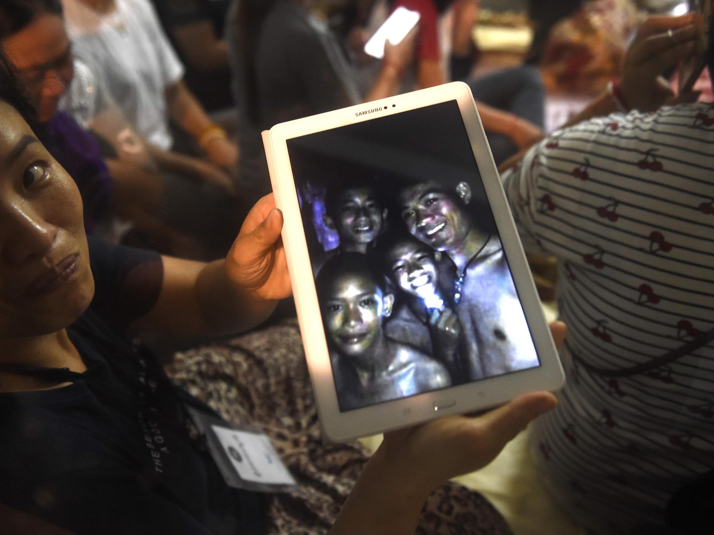 A happy family member shows the latest pictures of the missing boys taken by rescue divers inside Tham Luang cave after all members of the group were found alive ( AFP PHOTO / LILLIAN SUWANRUMPHALILLIAN SUWANRUMPHA/AFP/Getty Images)