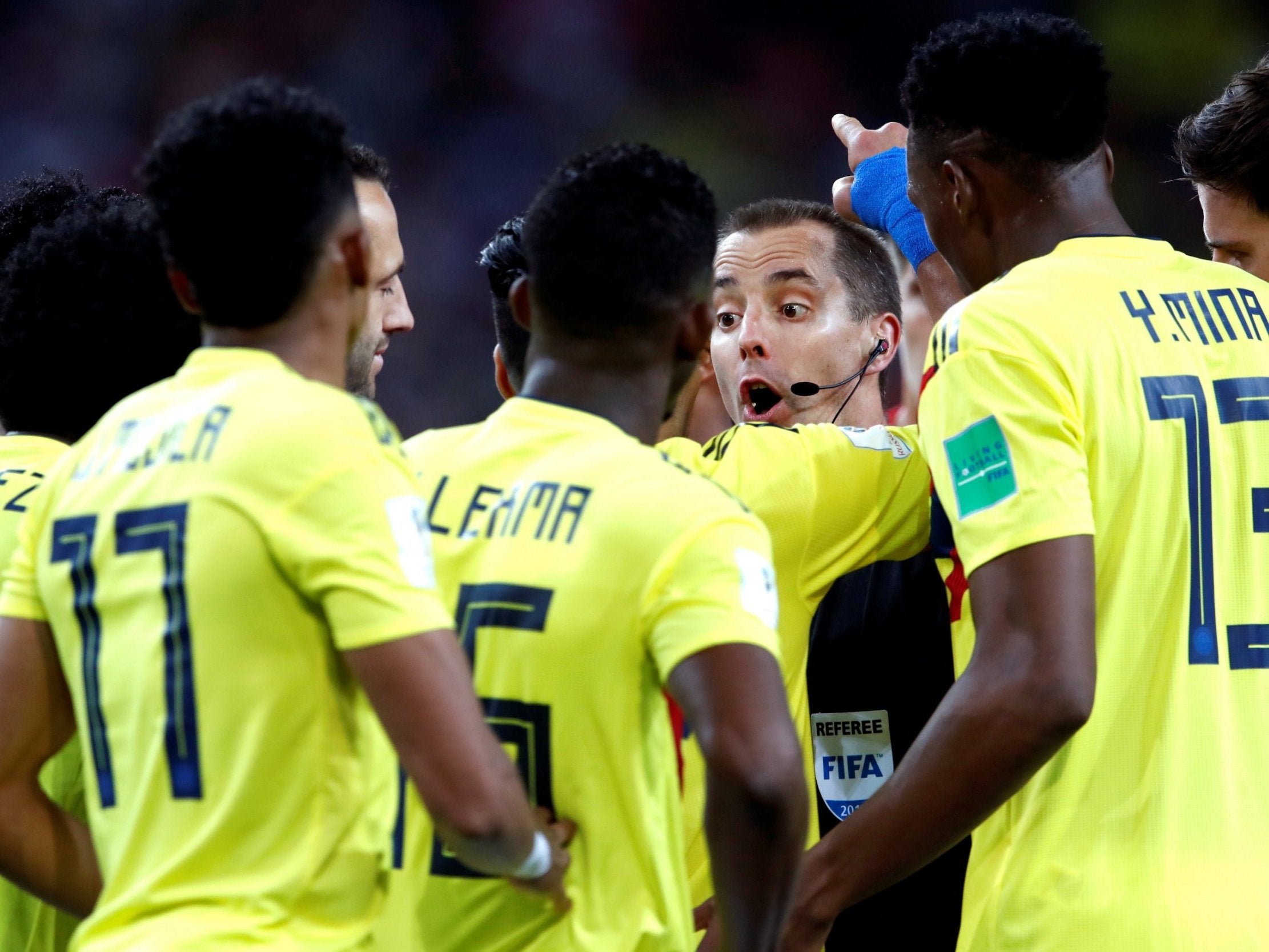 Colombia players surround referee Mark Geiger