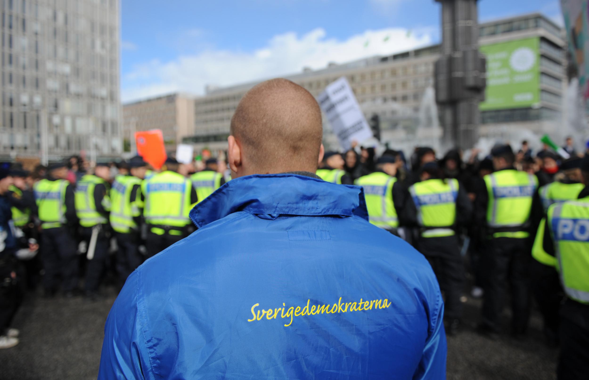 A supporter of the Sweden Democrats party stands behind a police line separating them from anti-racist protesters