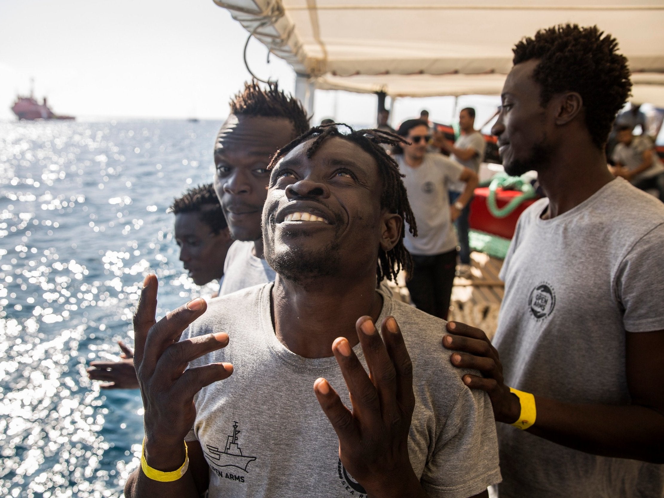 Migrants aboard the Open Arms aid boat as it approaches the port of Barcelona