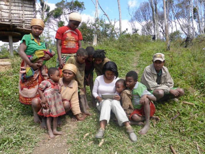 Co-author Rina Mandimbiniaina entering data from an interview for the study, watched by a participating household (S Rakotonarivo)