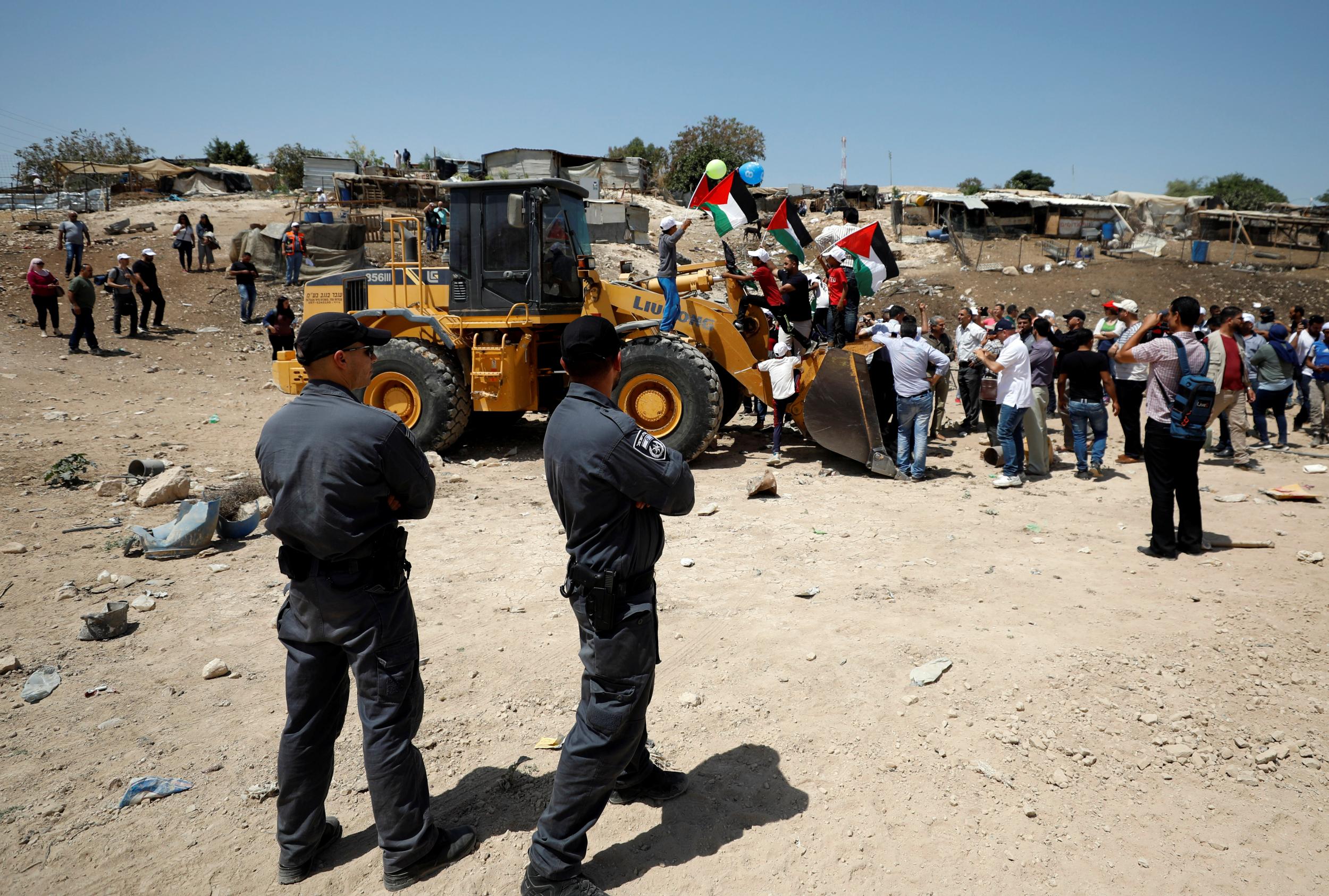 Palestinians ride on an Israeli bulldozer in the Bedouin village of Khan al-Ahmar in the occupied West Bank (Reuters)