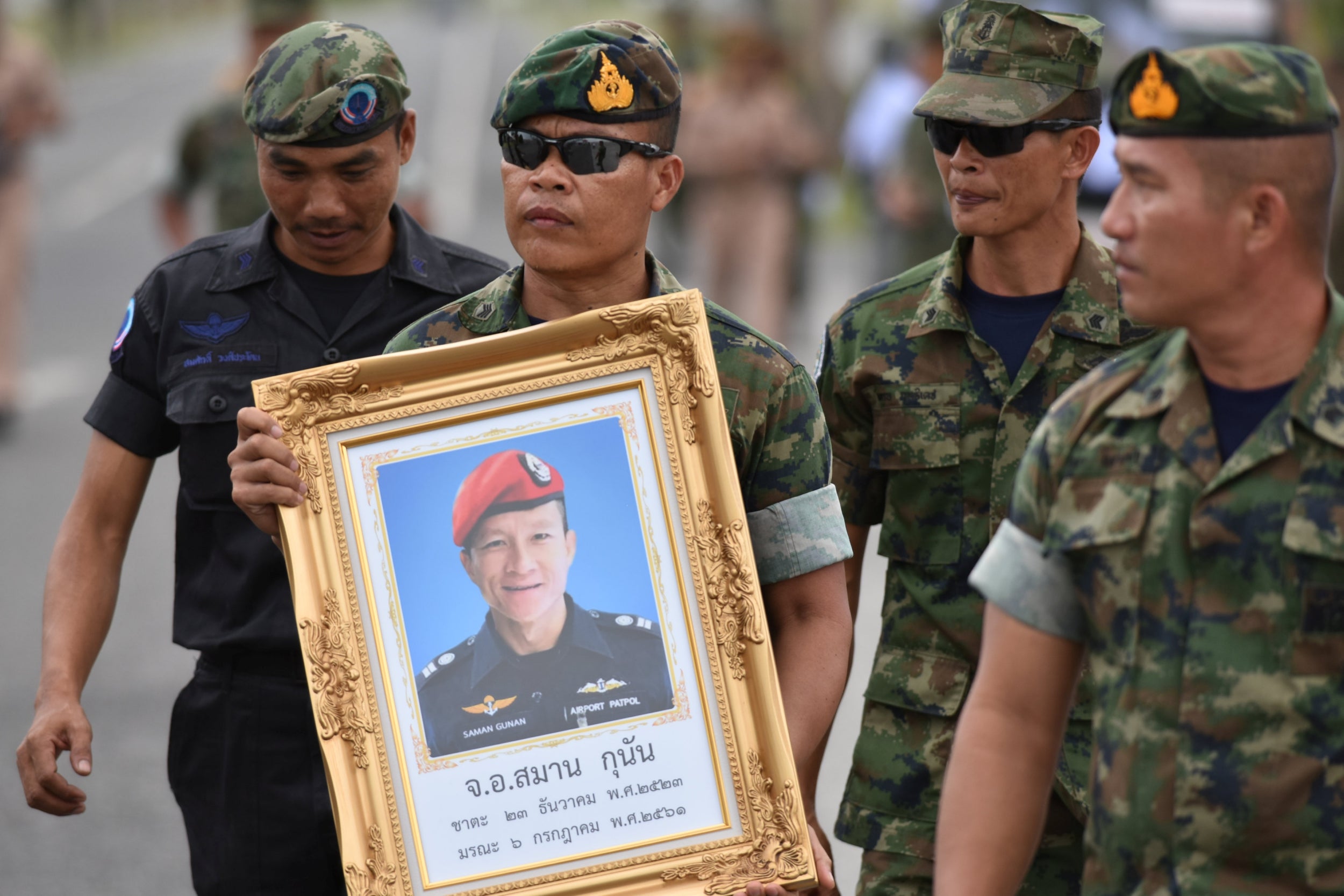 An honour guard hold up a picture of Samarn Kunan, 38, a former member of Thailand's elite navy Seal unit who died during the rescue operation