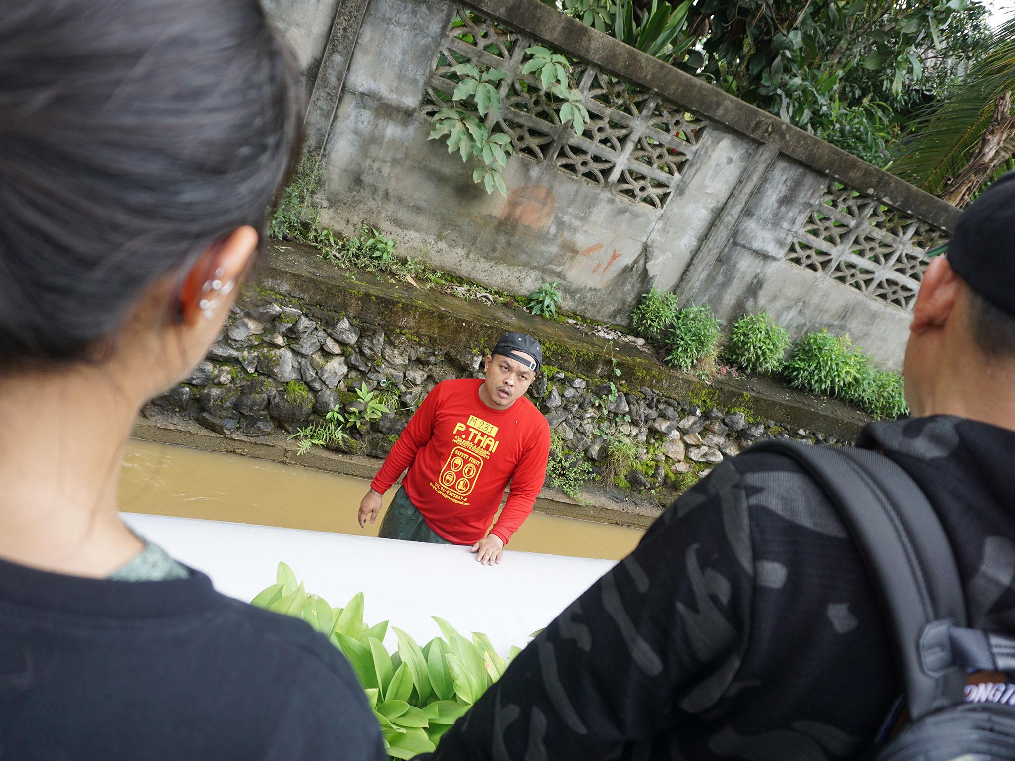 Pairojana Toontong and his daughter Sthpanik watch on as a volunteer guides a colleague through the inflated tube