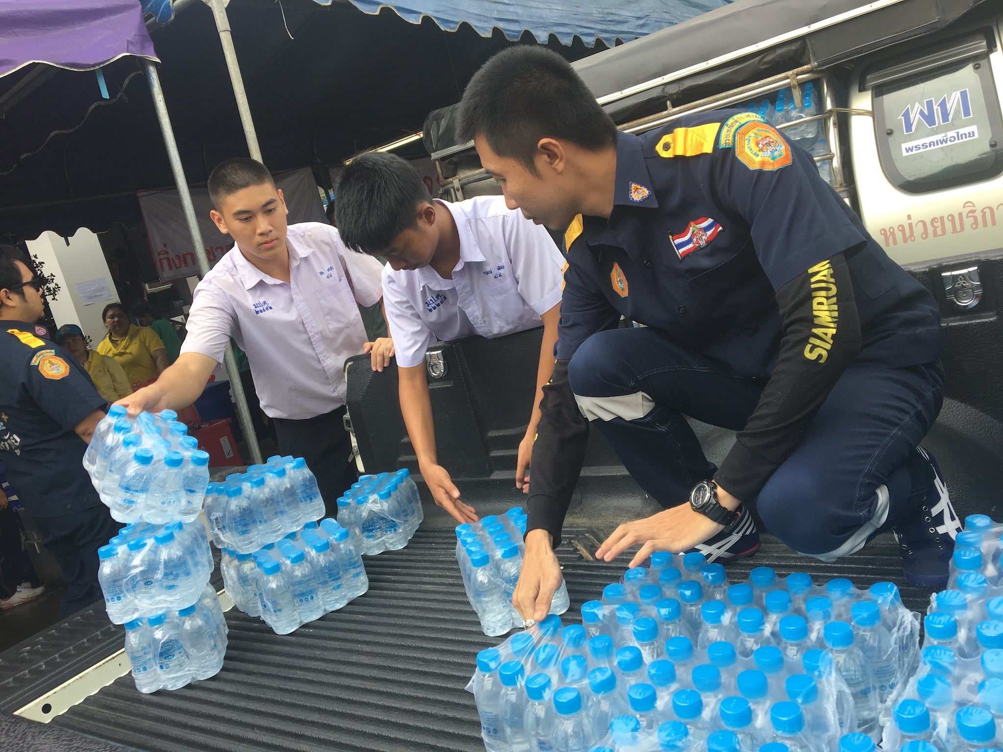 Wichai Saechao, left, helps to load a vehicle with water to take to rescue personnel. He says he 'always wondered what it would be like to go into the cave'