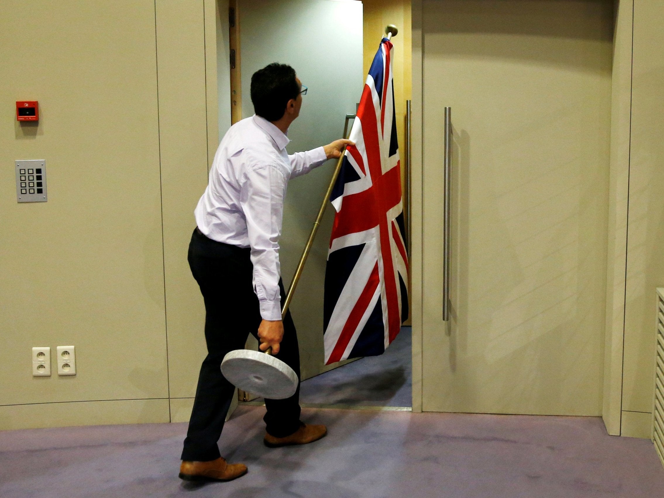 An official carries a Union Jack flag ahead of a news conference by Britain's Secretary of State for Exiting the European Union David Davis and European Union's chief Brexit negotiator Michel Barnier in Brussels