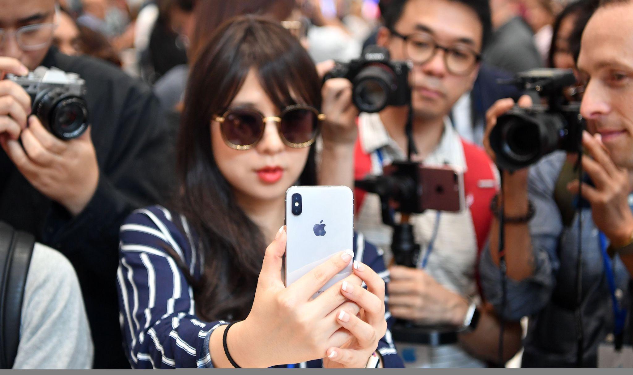 People take photos as a woman tests out a new iPhone X during a media event at Apple's new headquarters in Cupertino, California on September 12, 2017