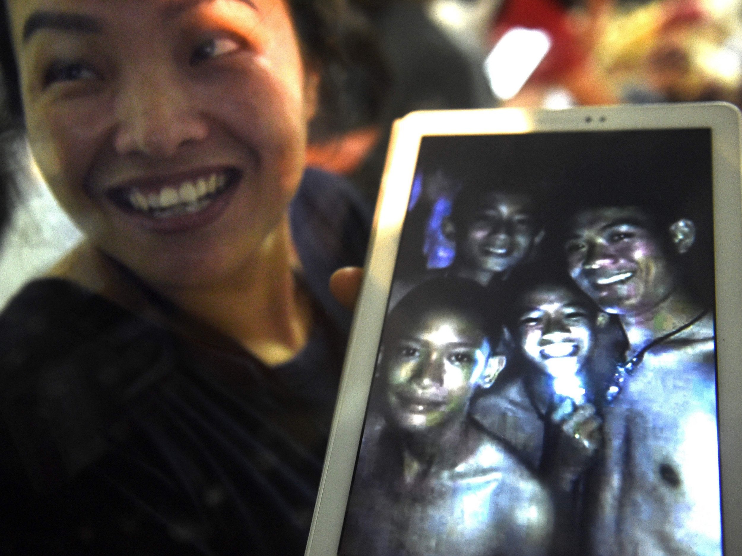 A family member shows a picture of four of the missing boys on the day they were discovered in the Tham Luang cave (AFP/Getty)